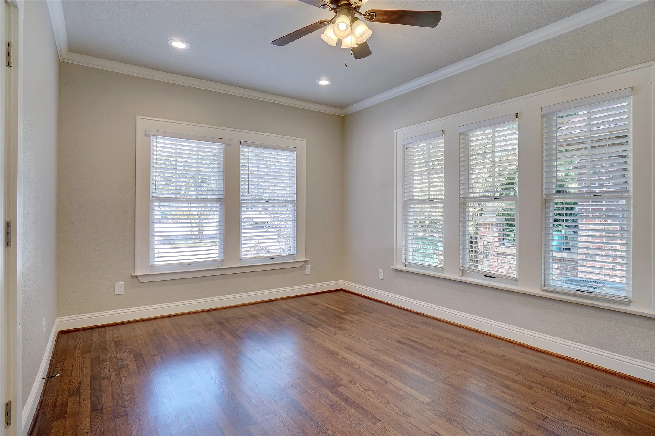 Wood-finish flooring, multiple windows with blinds, recessed lighting, ceiling fan, and crown molding
