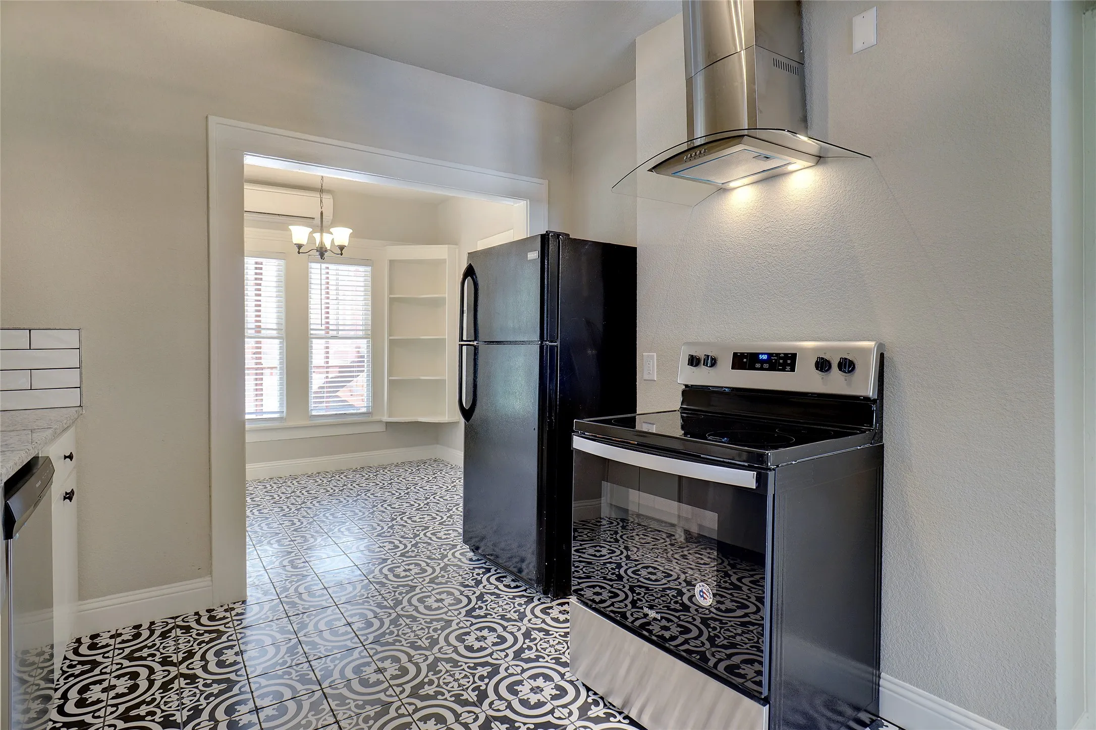 Kitchen featuring black and white patterned tile flooring, a stainless steel range hood, a black electric range, a black refrigerator, and white subway tile backsplash