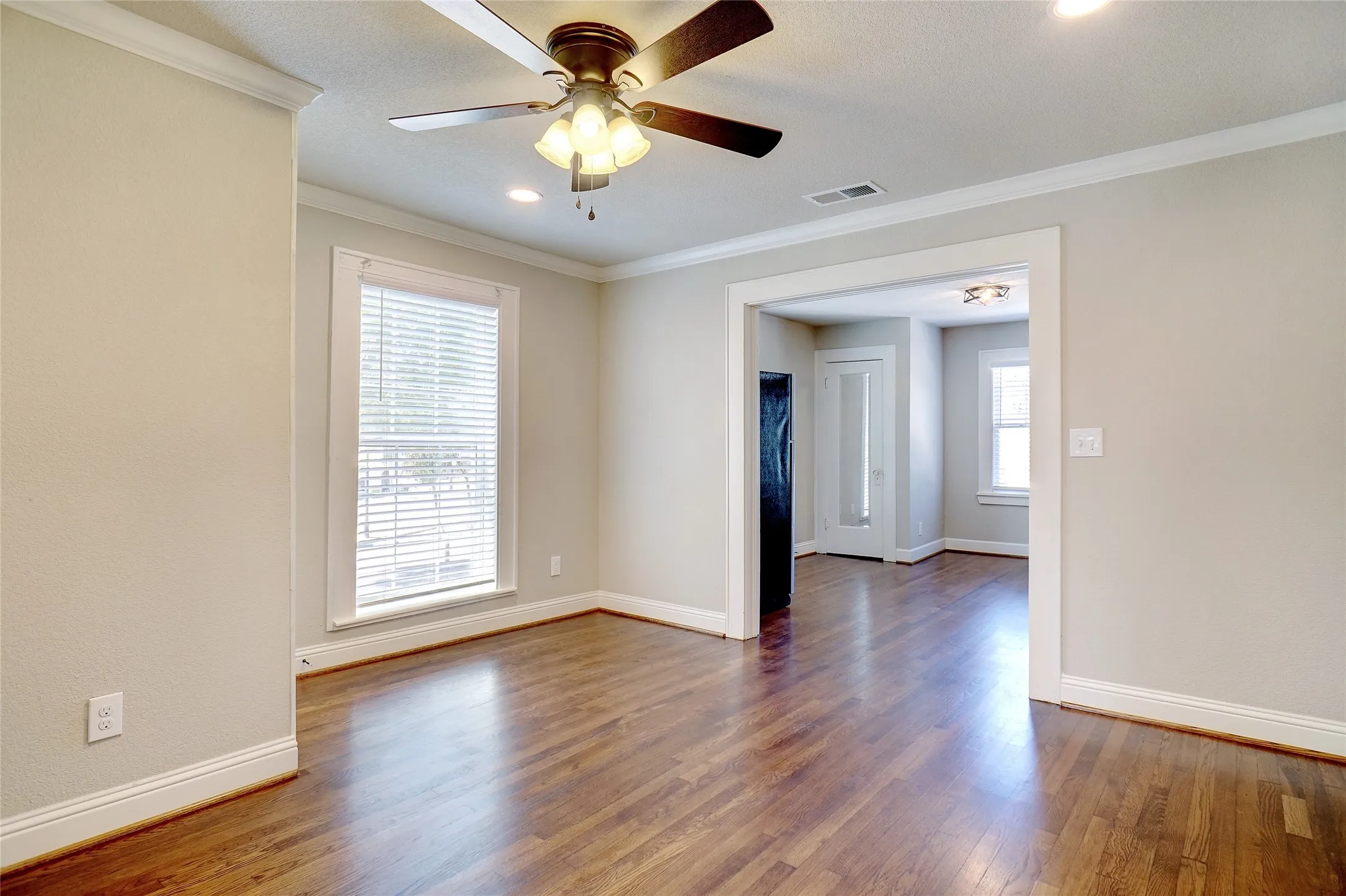 Hardwood flooring, crown molding, recessed lighting, ceiling fan, and a wide cased opening