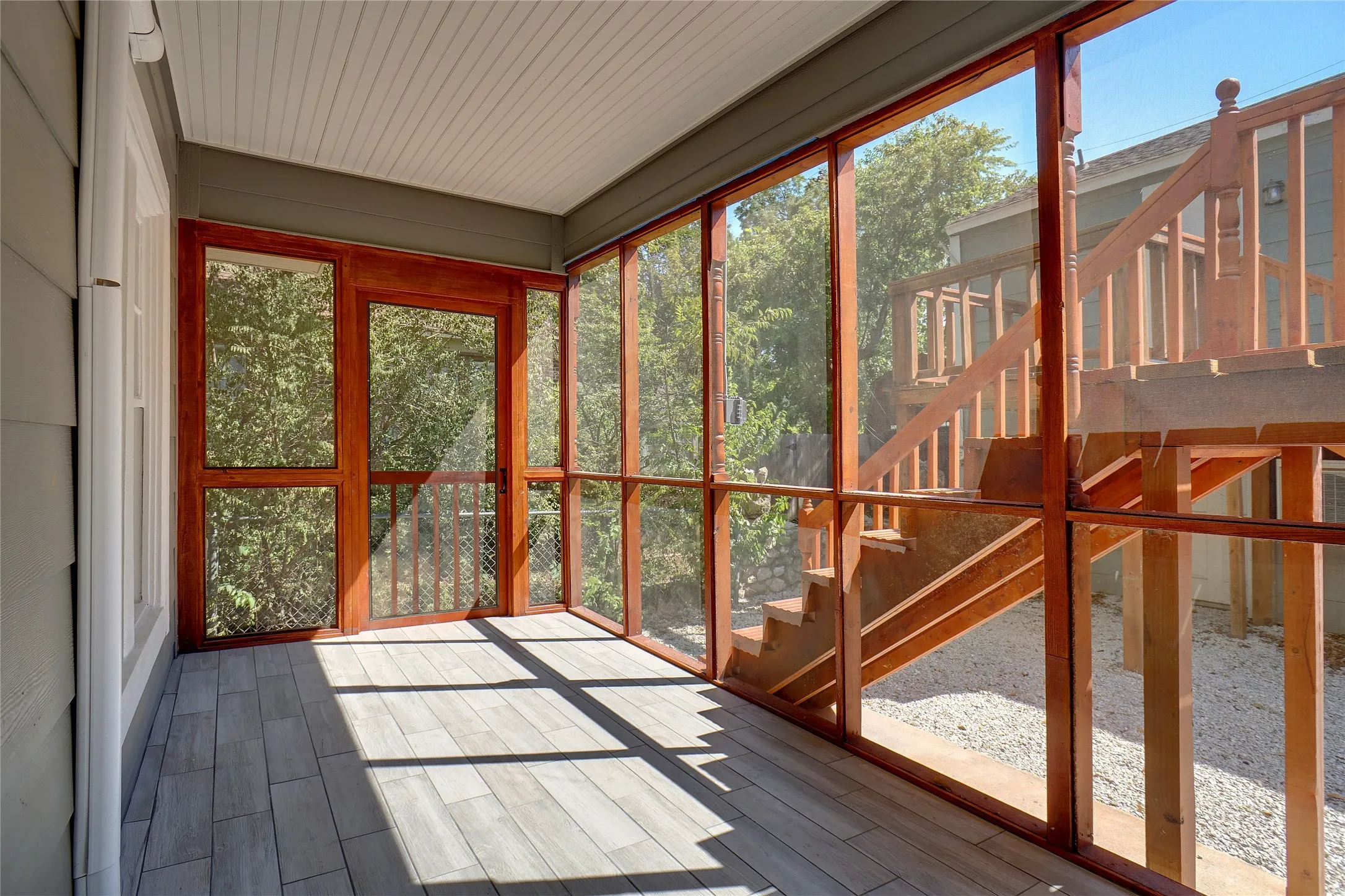 Screened porch with wood-finish flooring, wood-framed screens, and a wood-framed door
