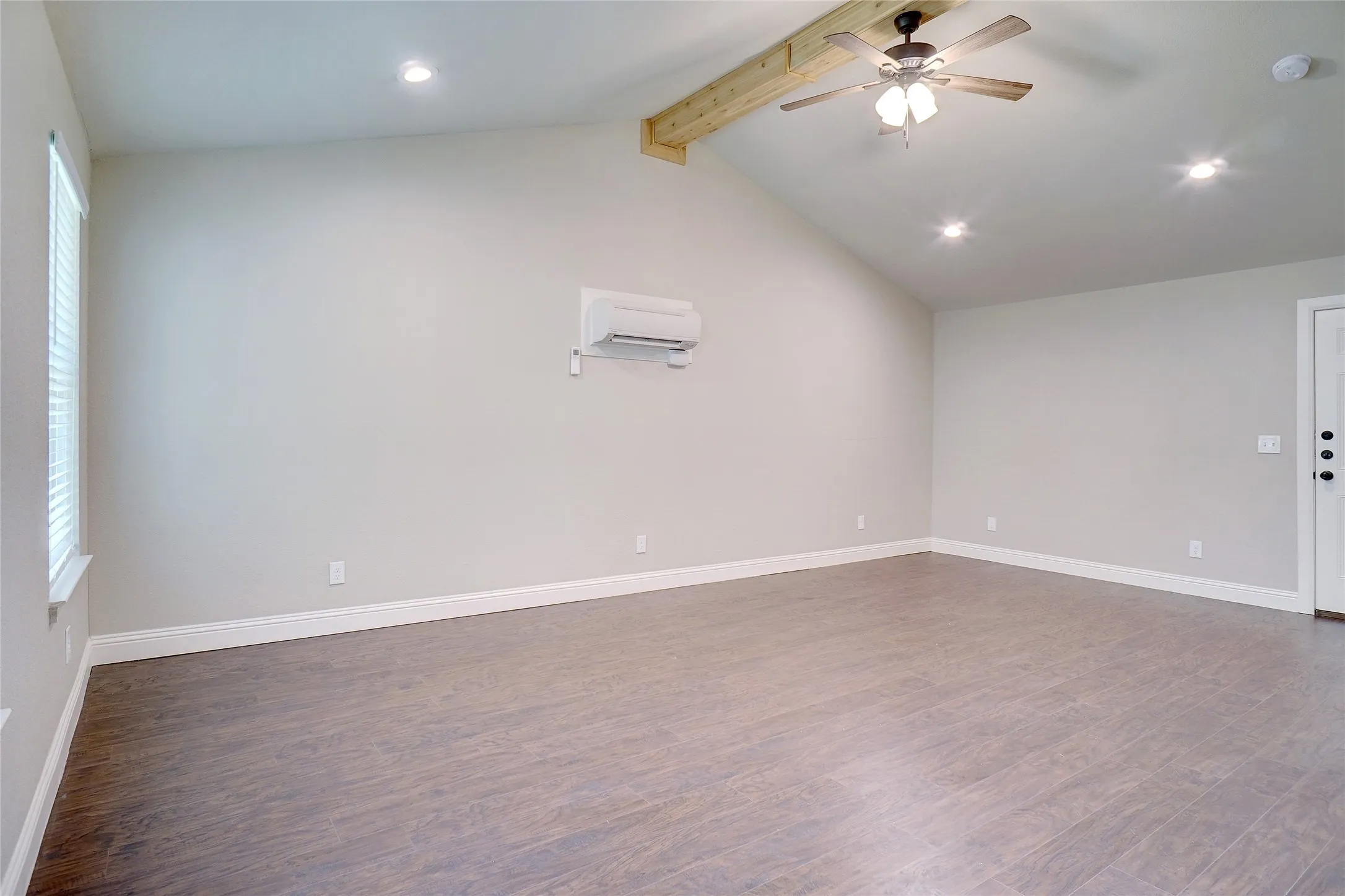 Vaulted ceiling with exposed wood beam, wood-finish flooring, recessed lighting, ceiling fan, and mini-split air conditioning unit