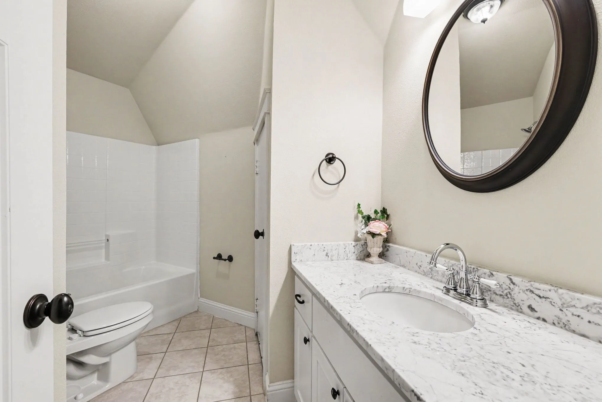 White vanity with dual doors and drawers, a light-colored stone-finish countertop, an undermount sink, and a chrome faucet