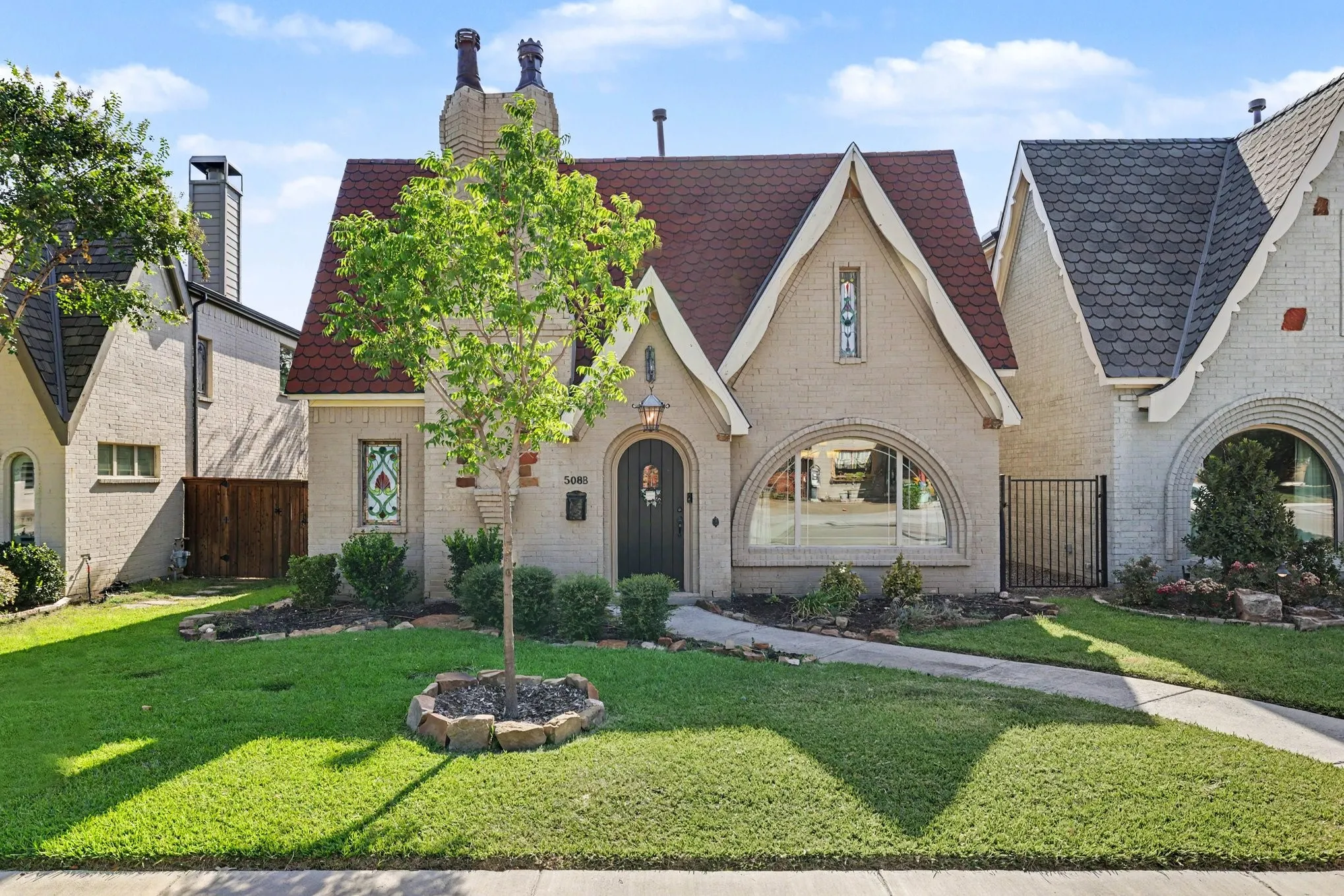 Gabled roofline with red tile shingles, arched entry door, and decorative stained glass window