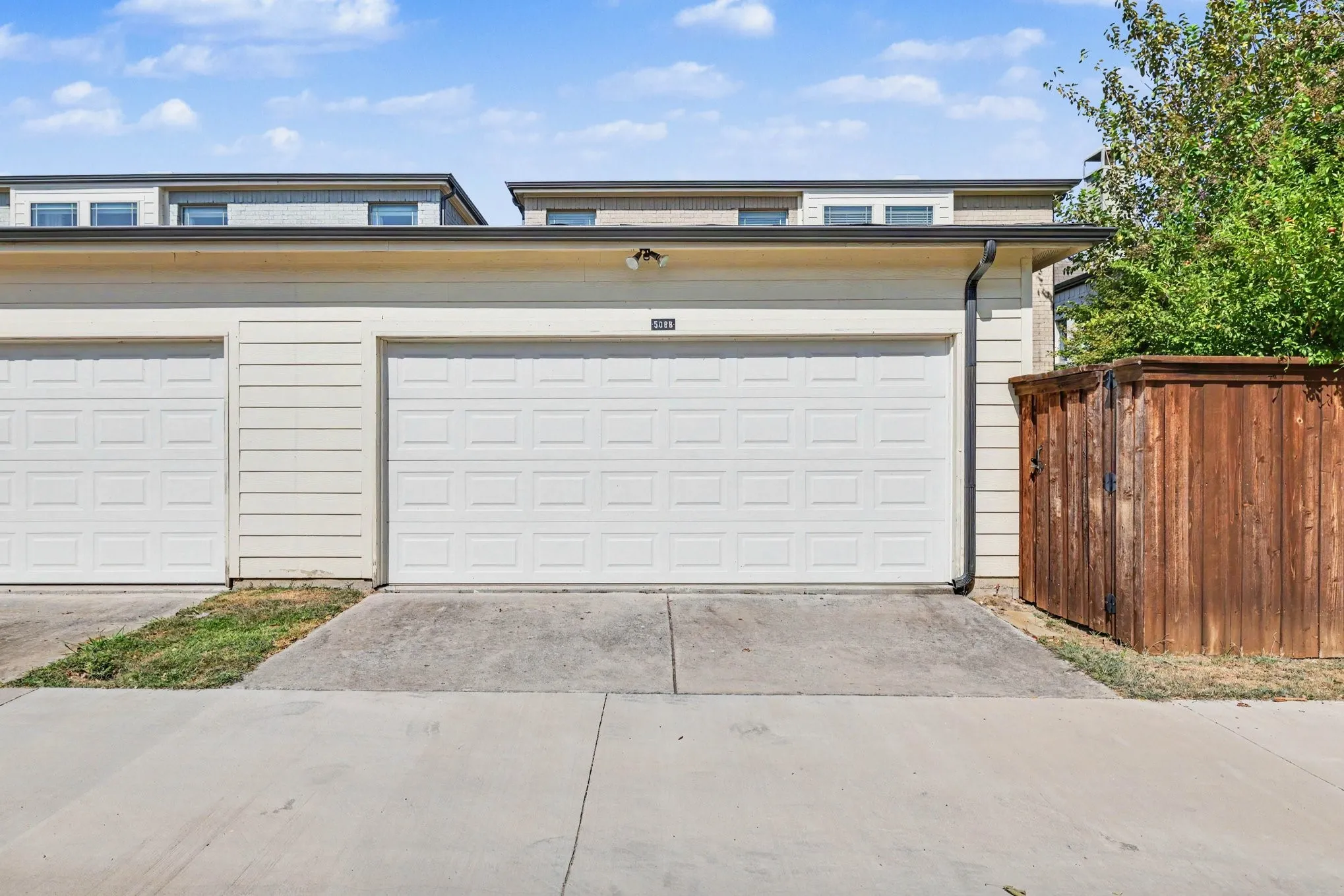 Two white paneled garage doors with concrete driveways