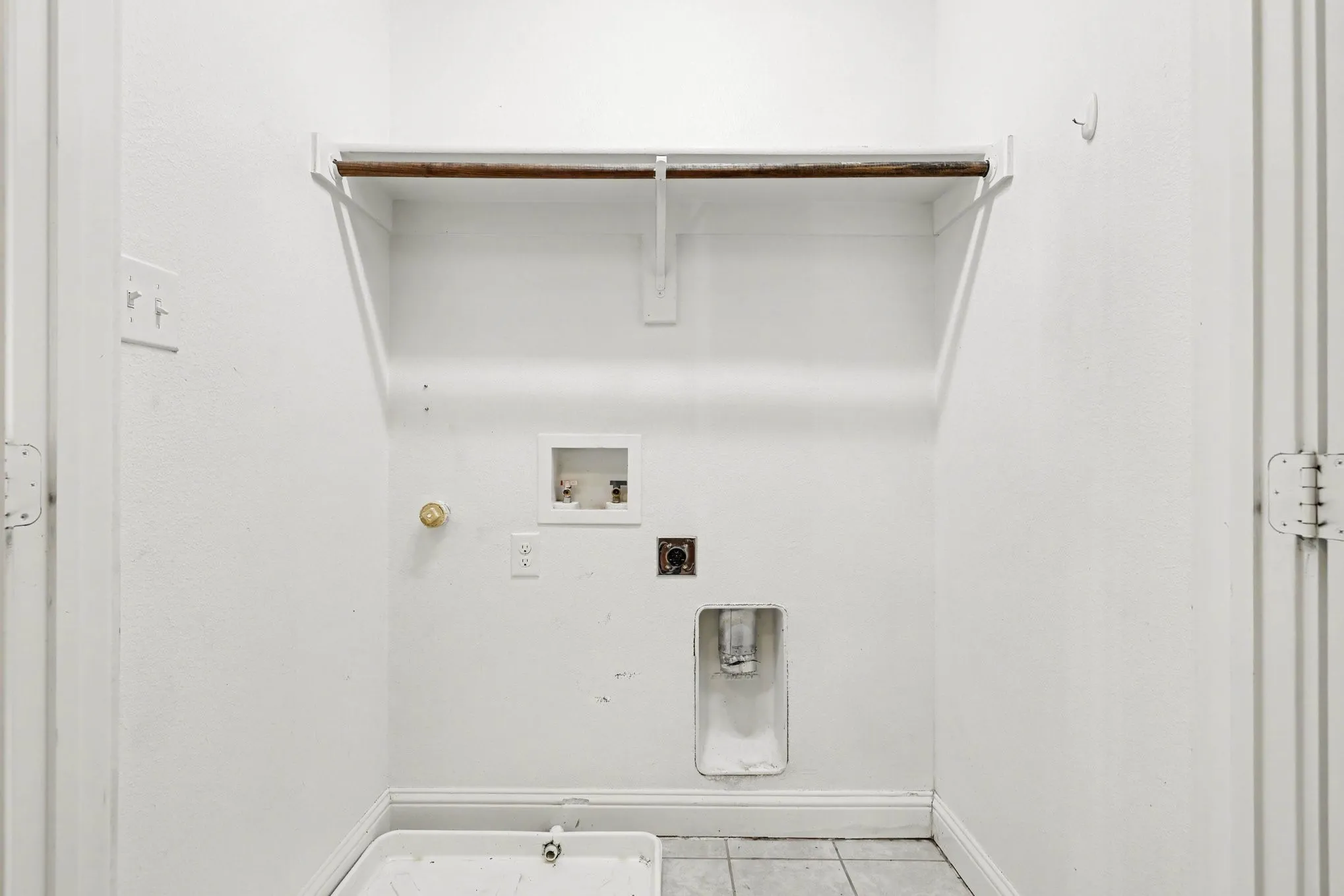 Laundry area featuring tile flooring, washer/dryer hookups, and a hanging rod with shelving