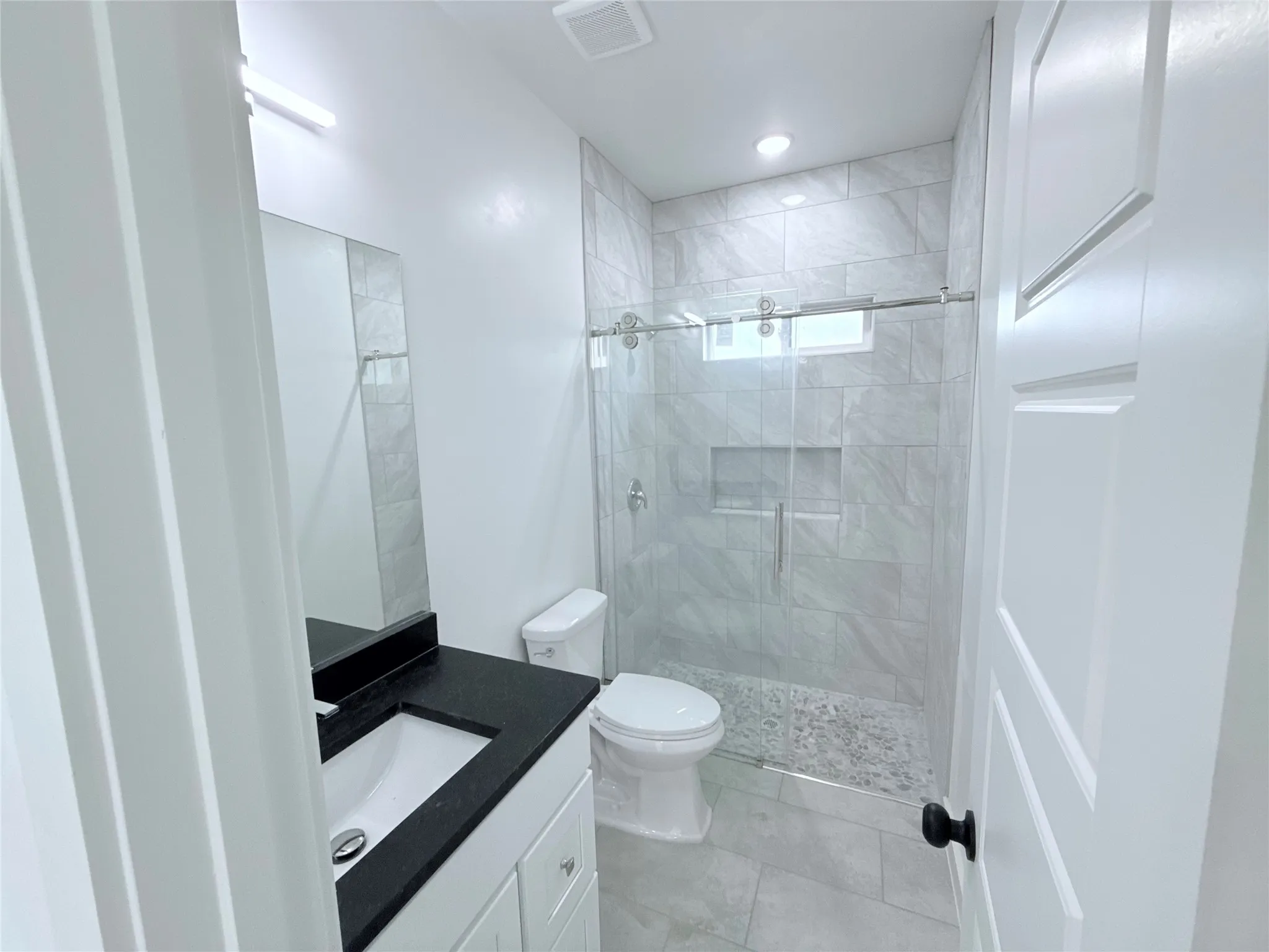 Bathroom featuring a single vanity with a dark countertop, white cabinetry, and a rectangular undermount sink