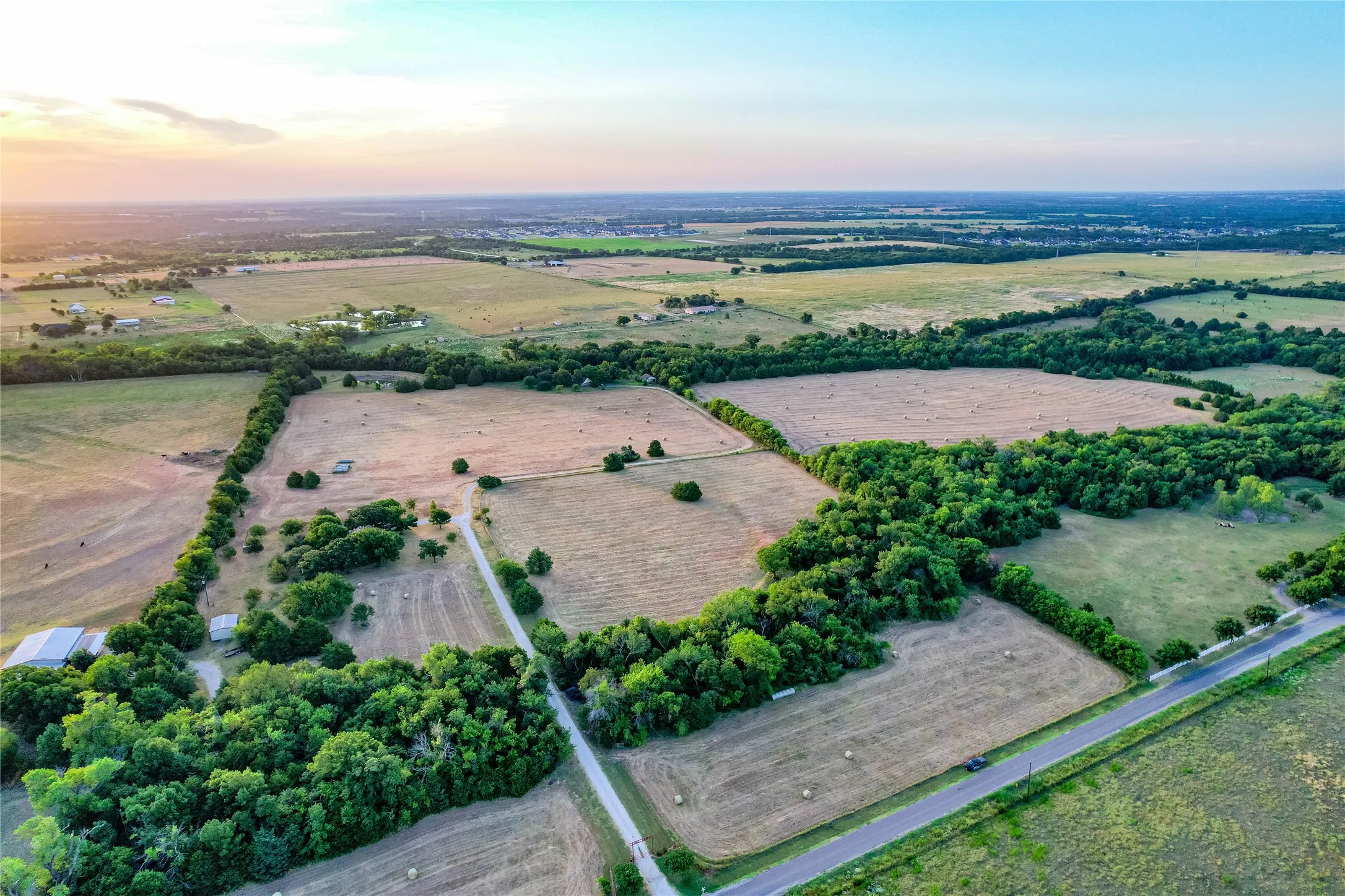 Expansive rural acreage featuring multiple clearings, mature tree lines, and a paved road frontage
