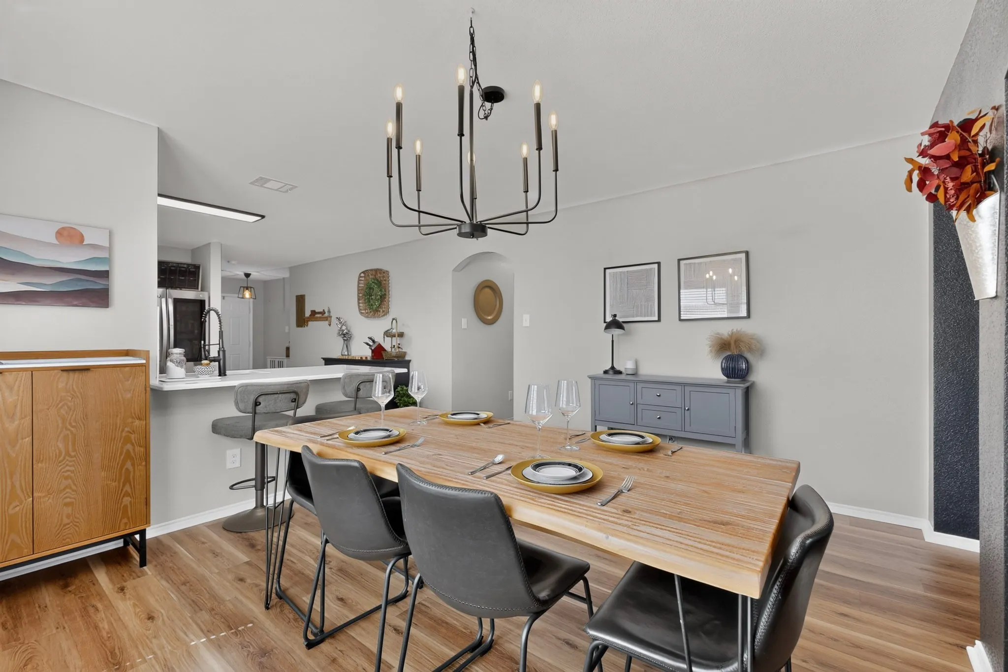 Open-concept dining area featuring wood-finish flooring, a contemporary chandelier, and an arched doorway