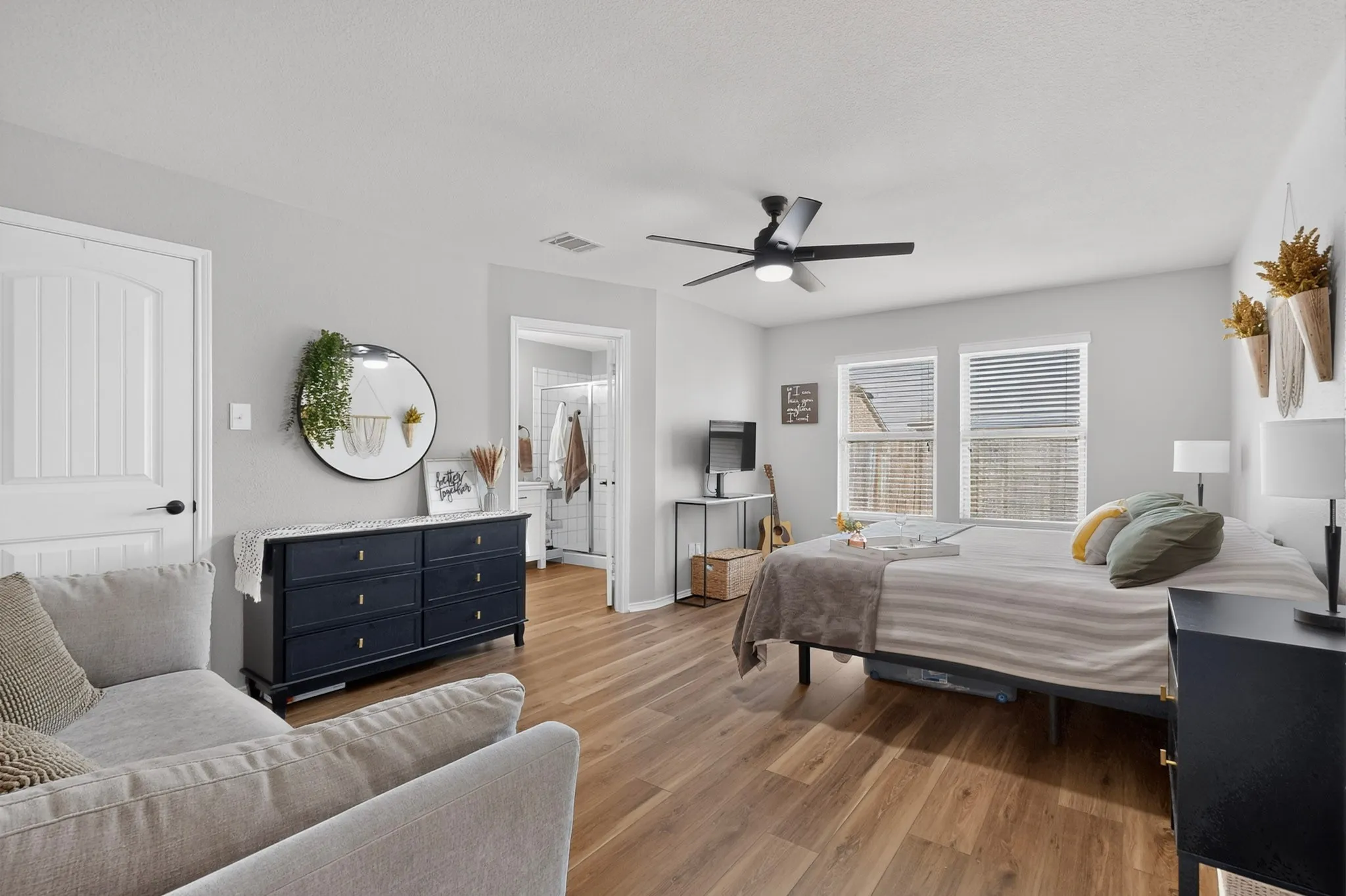 Wood-finish flooring, light grey walls, and a ceiling fan with integrated lighting