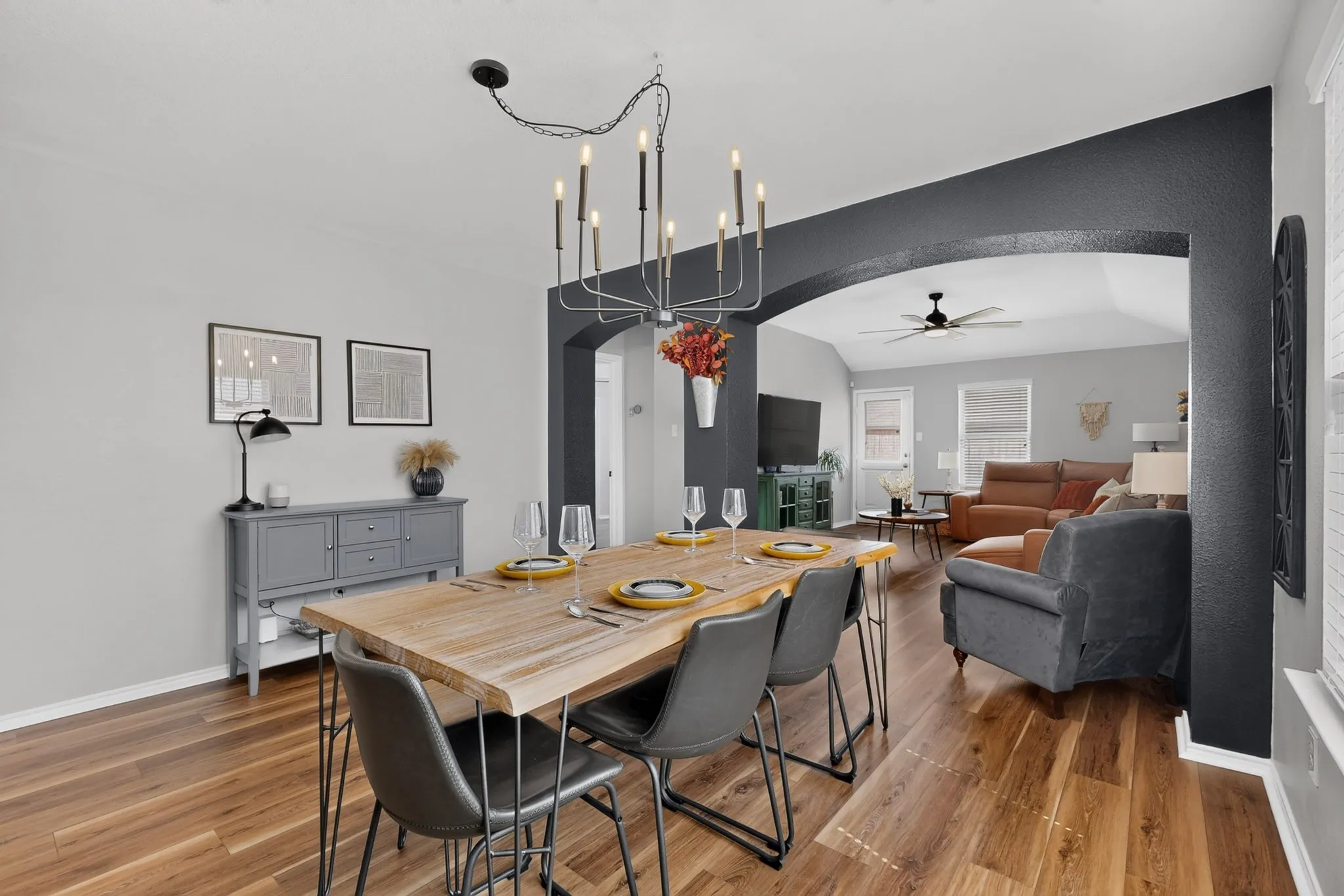 Wood-finish flooring throughout, arched entryway, contemporary chandelier, built-in cabinetry, and ceiling fan
