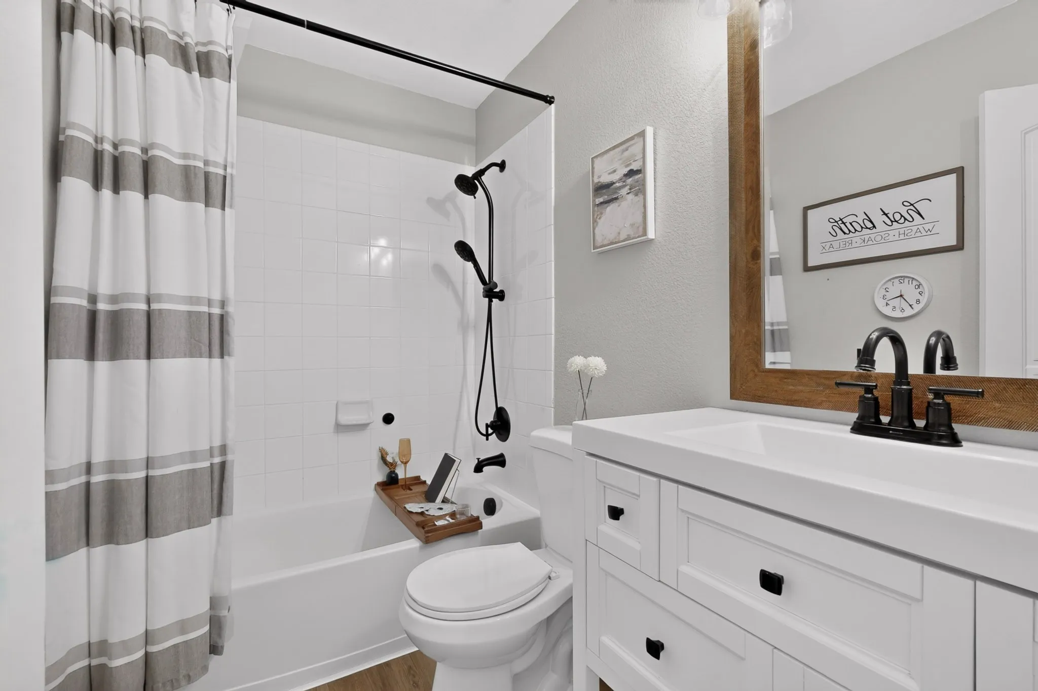 White vanity with an integrated sink and matte black faucet, framed mirror, and a tiled shower-over-tub with matte black fixtures