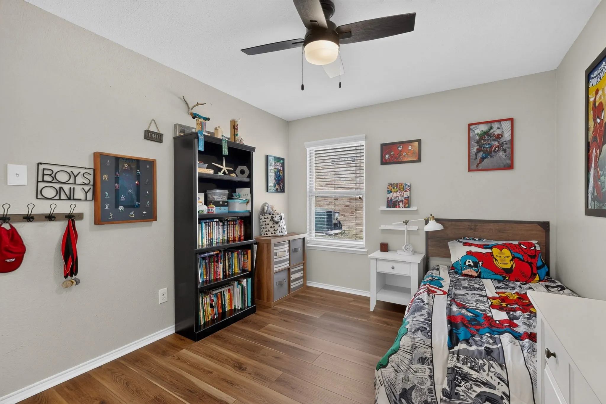 Wood-finish flooring, ceiling fan with integrated lighting, window with blinds, and light-toned wall paint