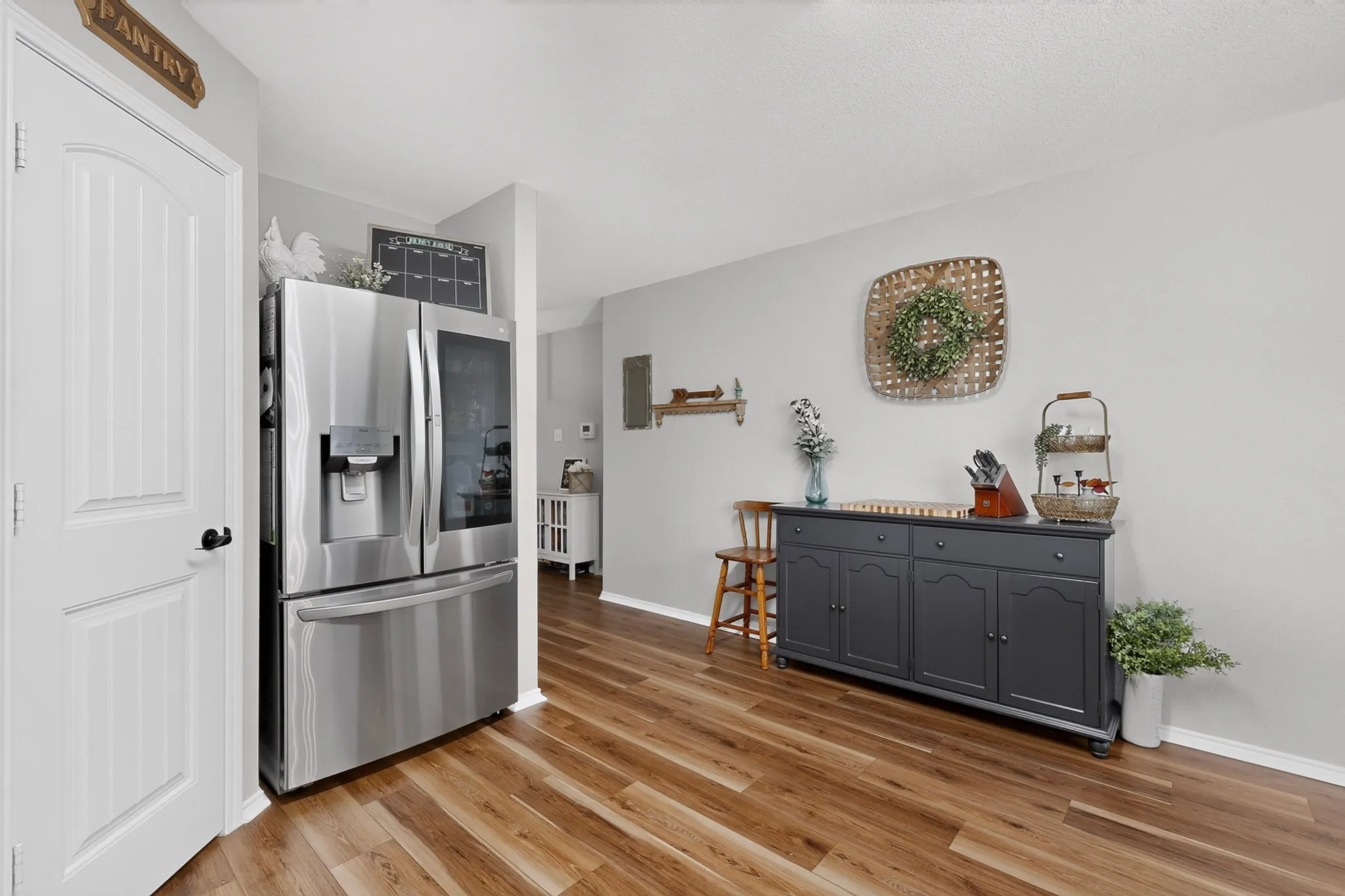 Wood-finish flooring, white paneled door, light gray walls, and built-in white baseboards