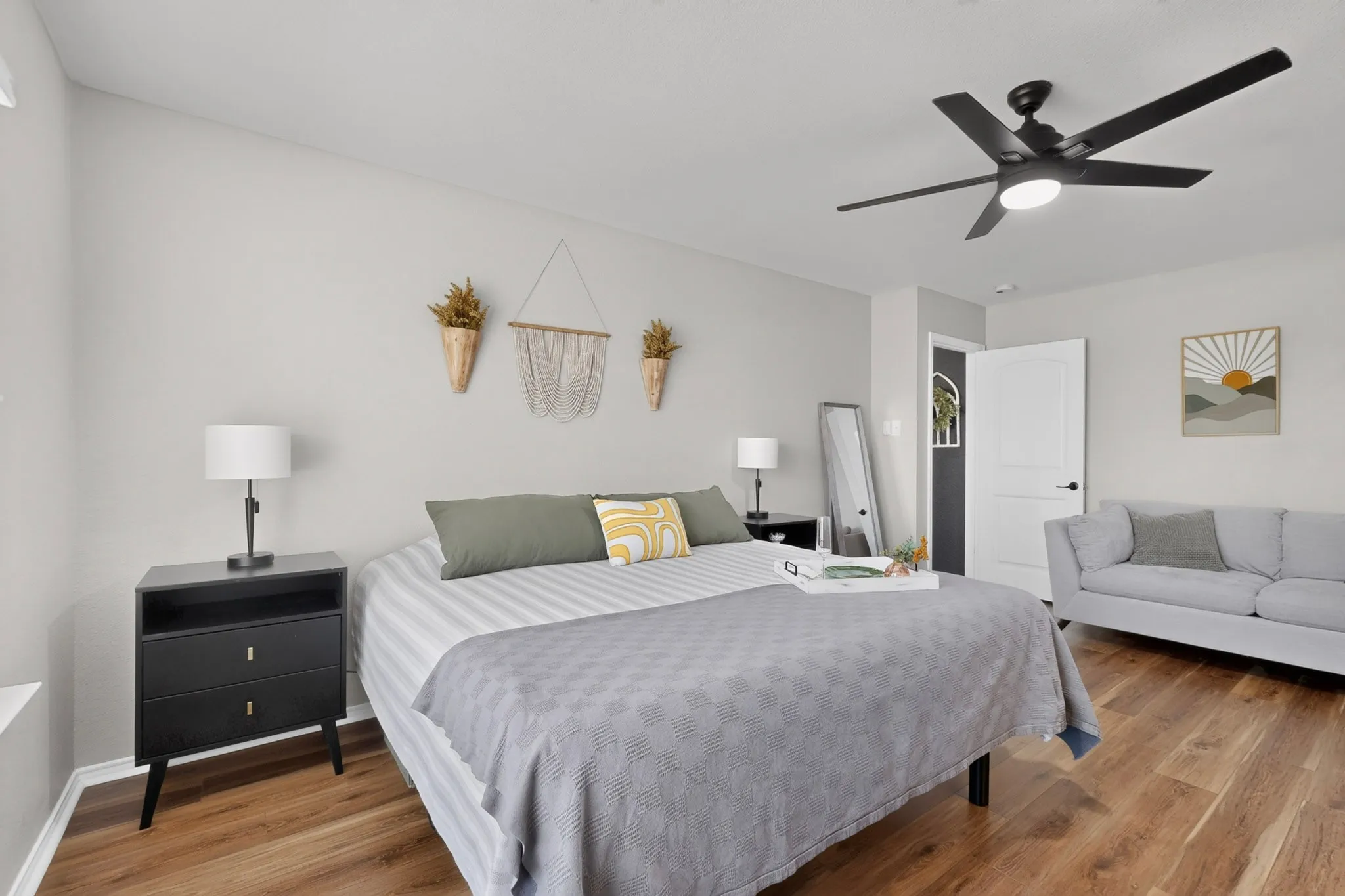 Wood-finish flooring, ceiling fan with integrated lighting, flat panel interior doors, and neutral wall tones