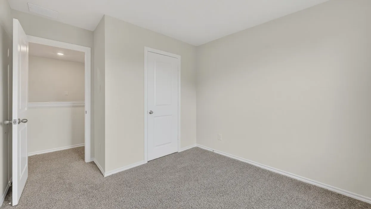 Neutral wall paint, gray carpeting, a two-panel interior door, and a built-in closet with shelving