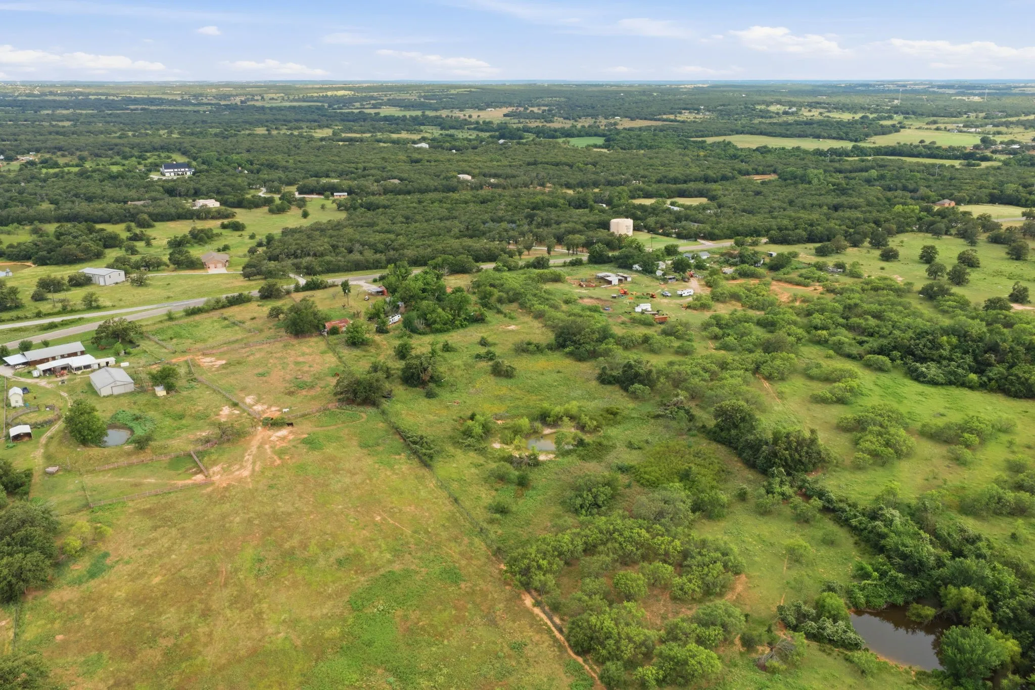 Expansive rural landscape featuring wooded areas, open fields, and multiple ponds