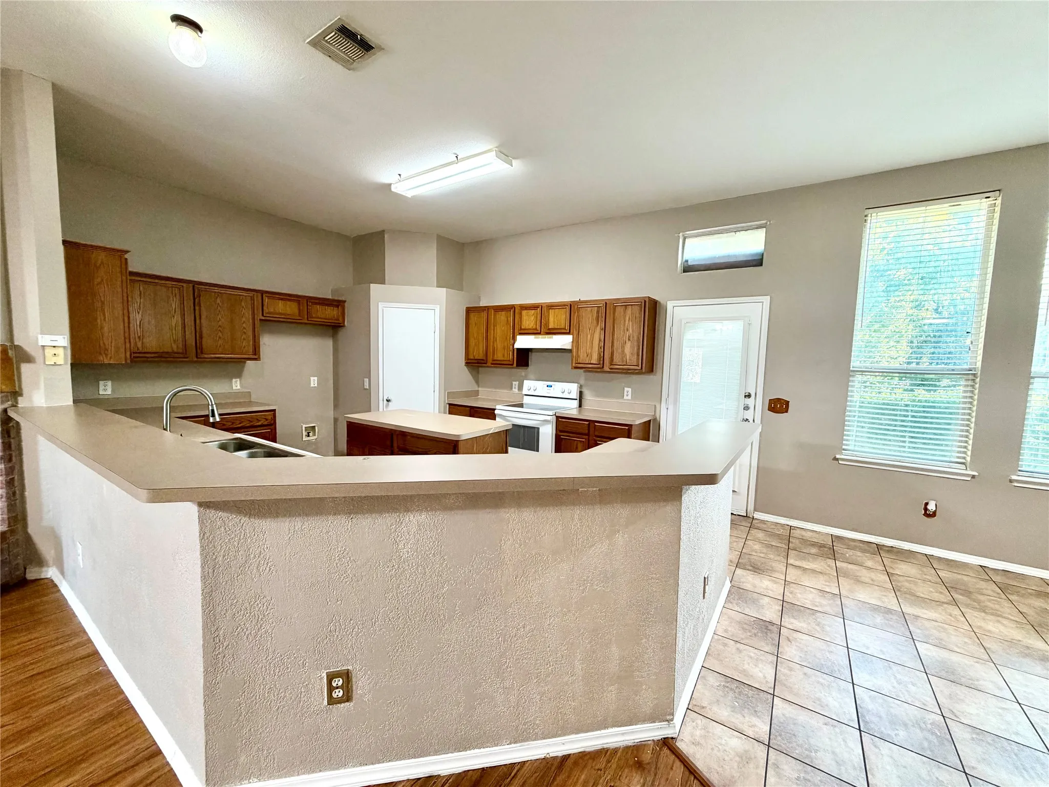 Kitchen featuring wood cabinetry, a central island, a breakfast bar, stainless steel sink, and tile flooring