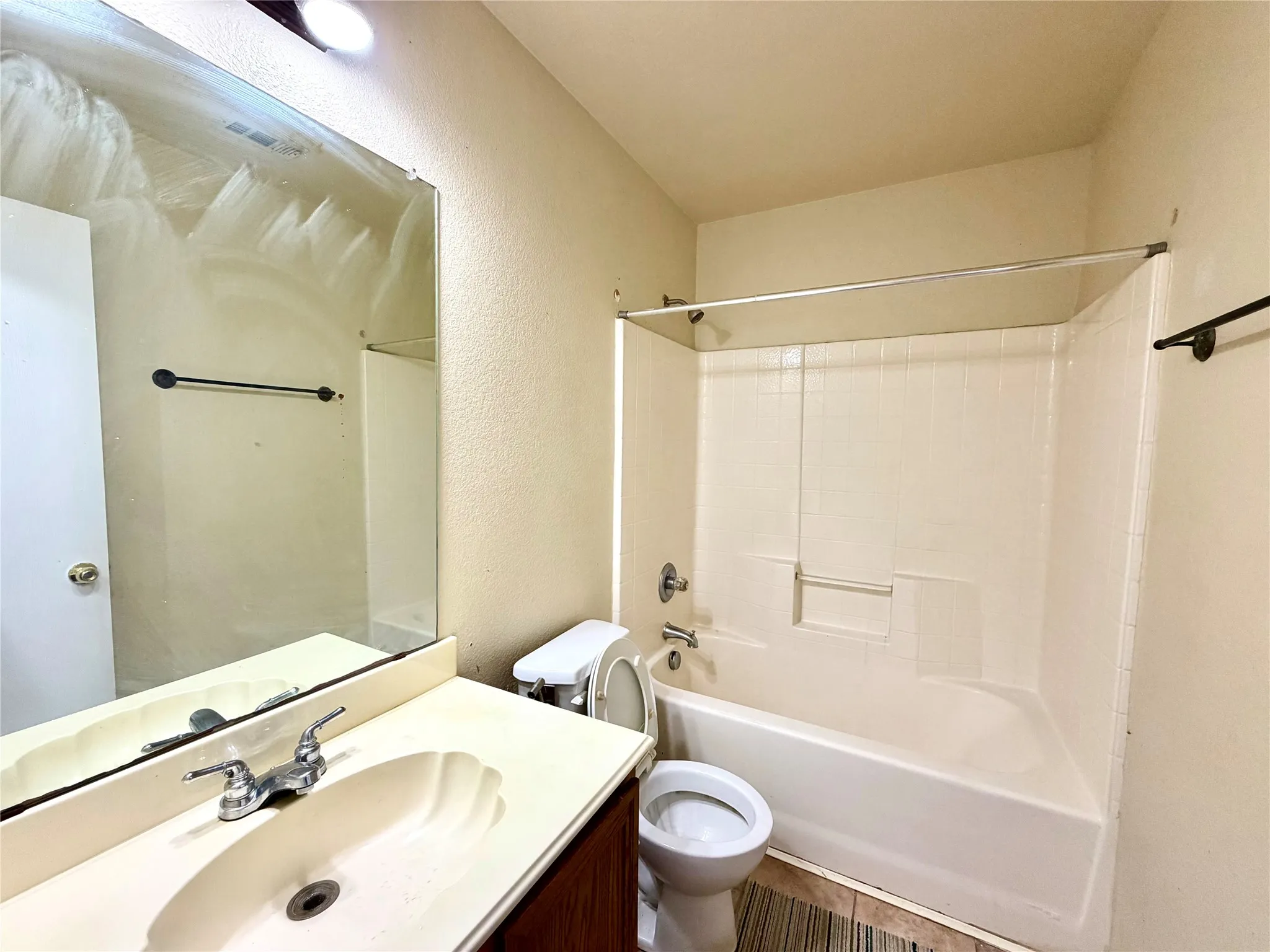 Vanity with integrated sink, chrome faucet, and expansive wall-mounted mirror