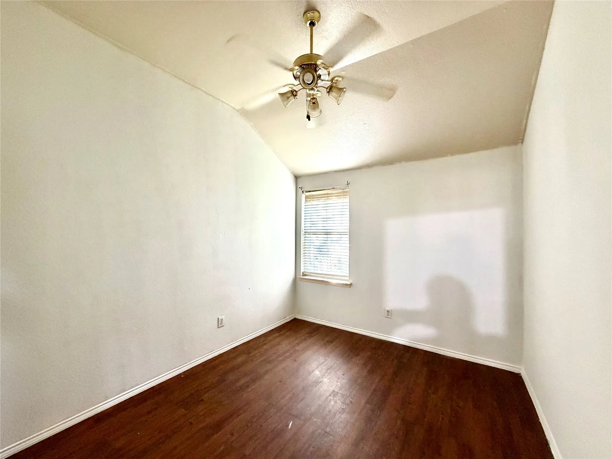 Vaulted ceiling with a ceiling fan, window with blinds, and wood-finish flooring