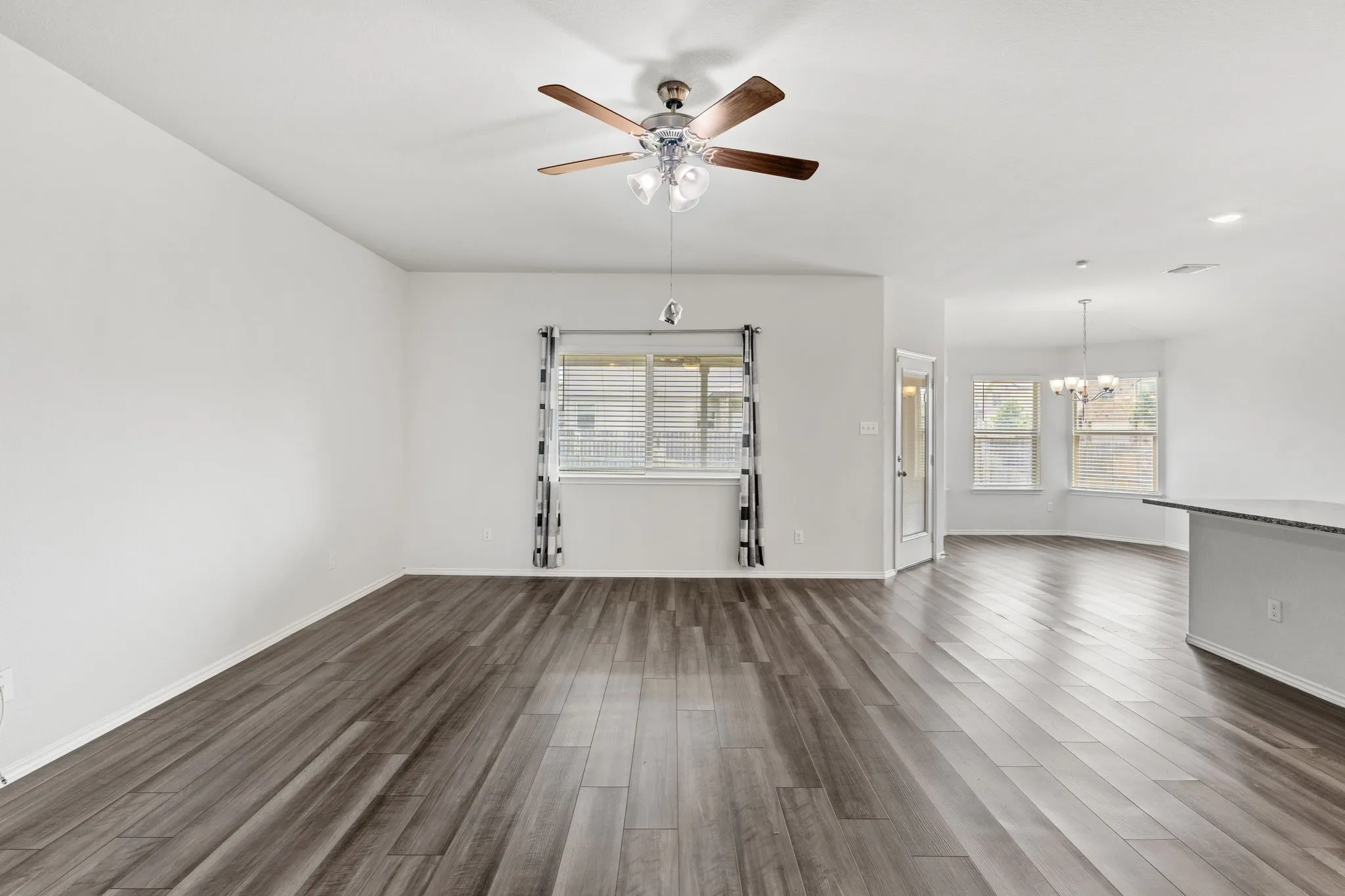 Wood-finish flooring throughout, modern ceiling fan, and multiple windows with blinds