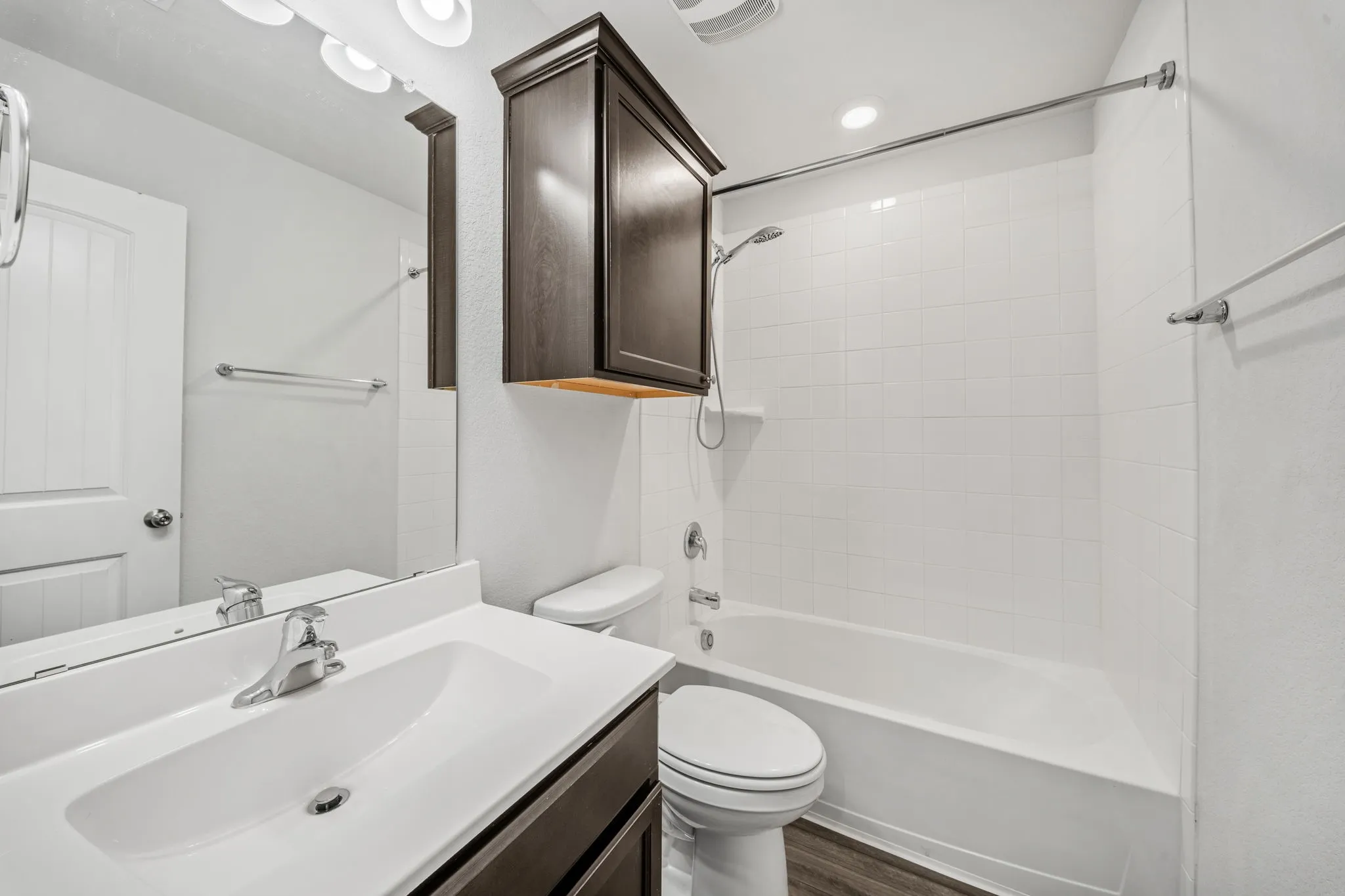 Bathroom featuring a vanity with an integrated sink, polished chrome faucet, full-width mirror, and a built-in cabinet