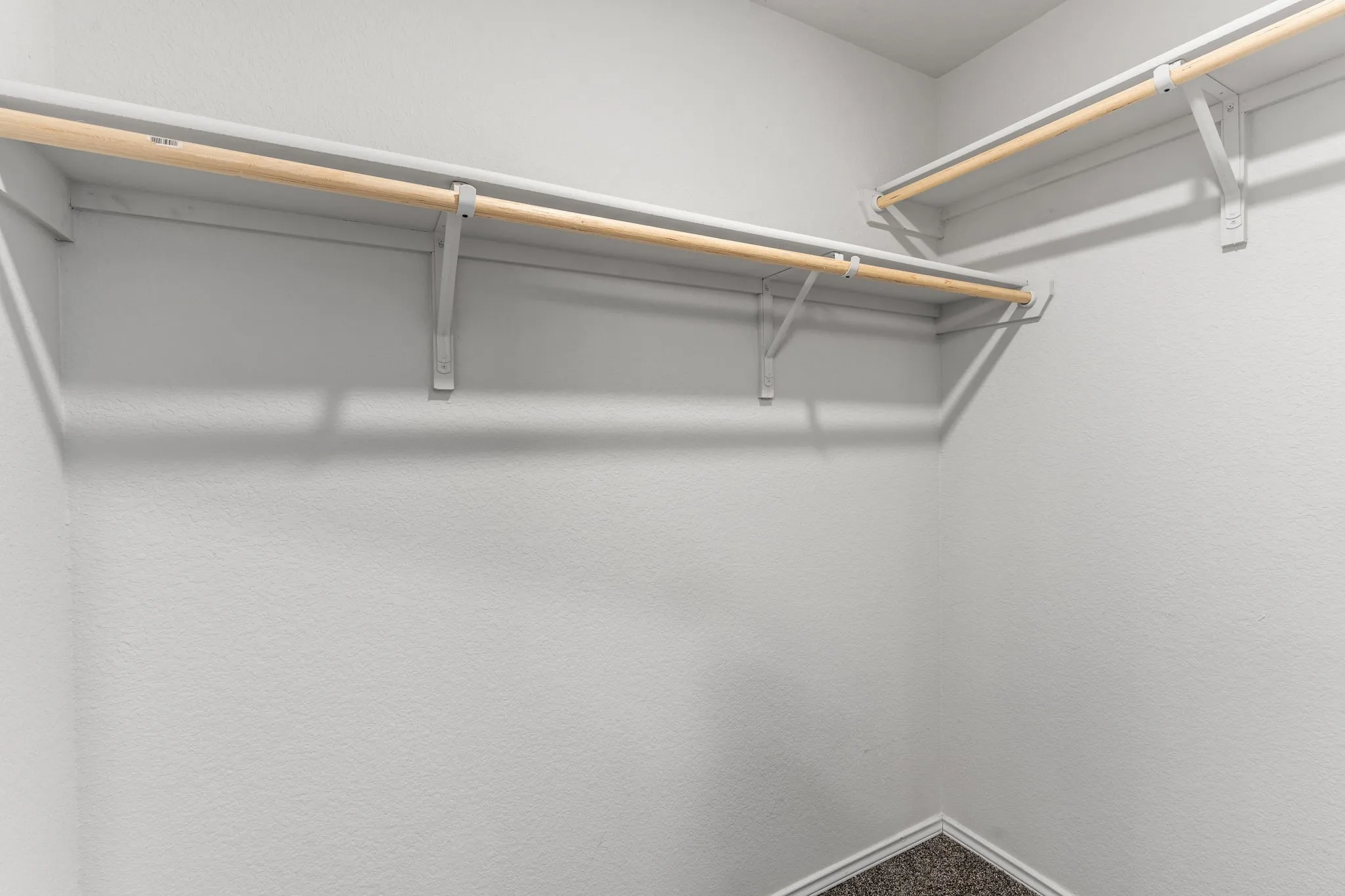 White painted walls with multiple wooden hanging rods and shelving