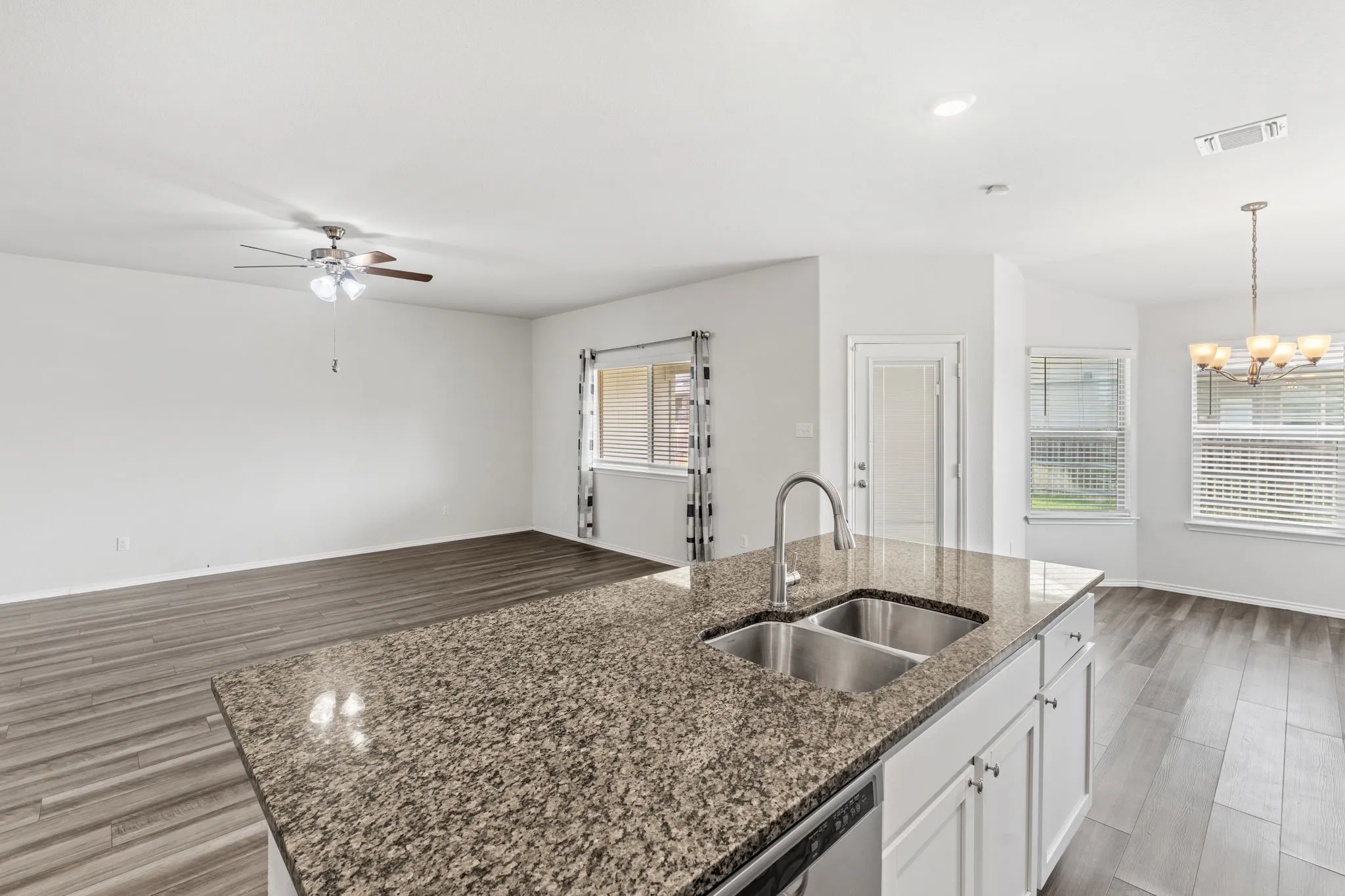 Kitchen island with granite-finish countertop, dual stainless steel sink, and white cabinetry
