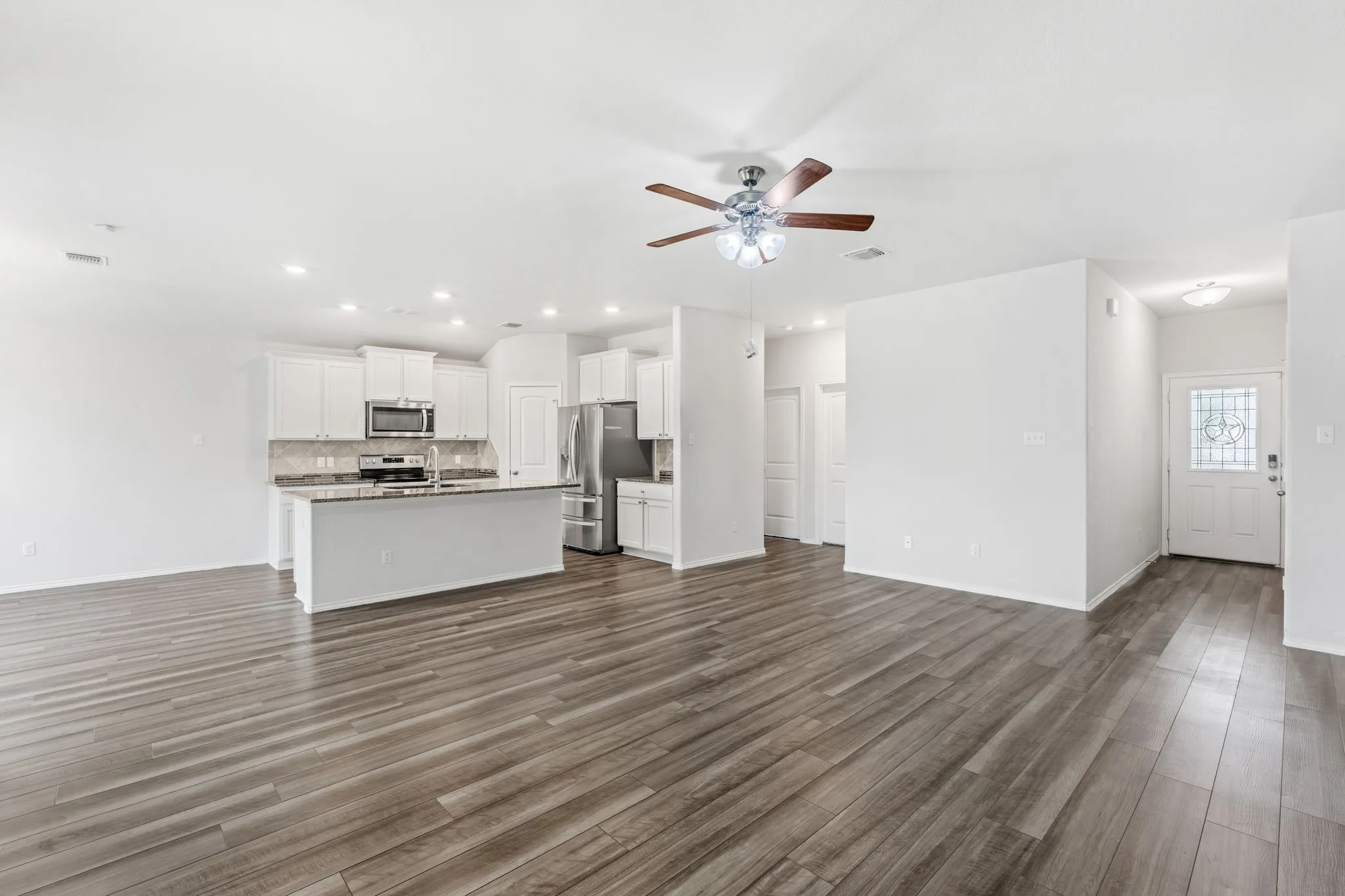 Open-concept living space featuring wood-finish flooring, recessed lighting, and a ceiling fan
