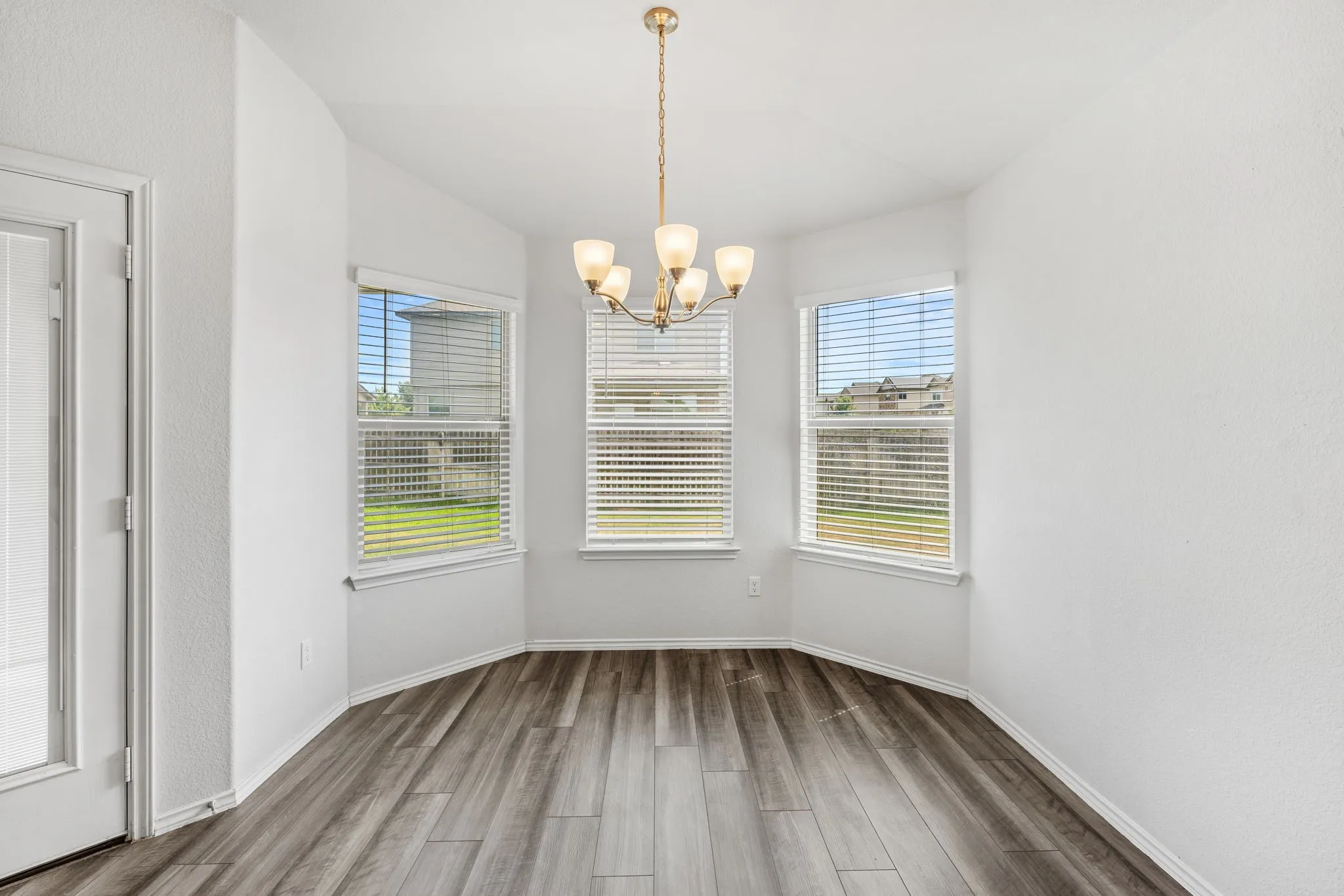 Recessed lighting fixture, three large windows, wood-finish flooring, and a glass-paneled door