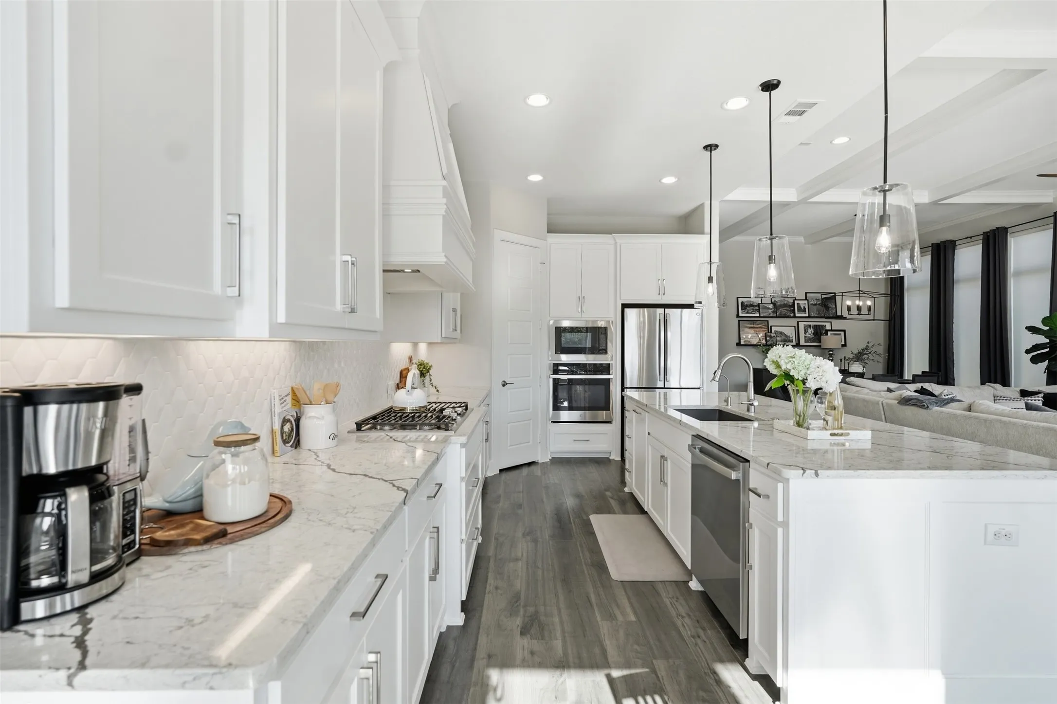 White cabinetry, granite countertops, stainless steel appliances, wood-finish flooring, and recessed lighting