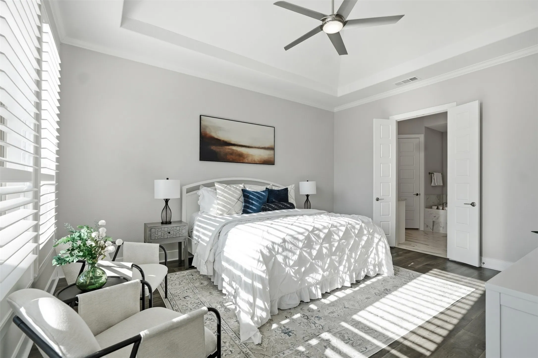 Tray ceiling with crown molding, ceiling fan, white plantation shutters, and double doors to additional space