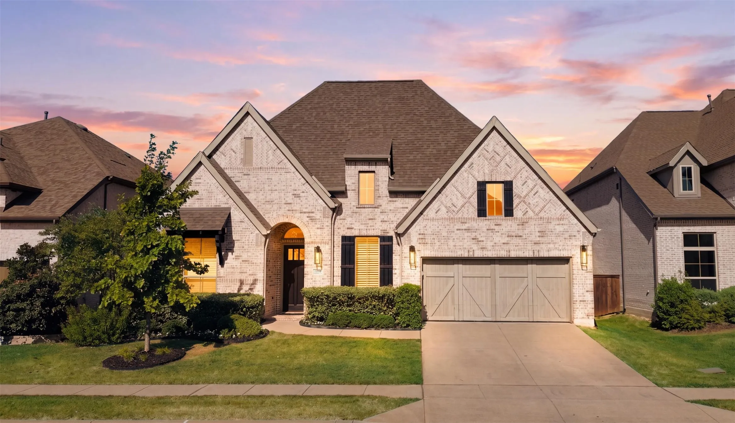 Welcome to the beautiful 3208 Alexandra Lane, Celina, TX 75009 - Light-tone brick exterior with dark shingle roofing, arched entry, decorative garage door, and manicured landscaping