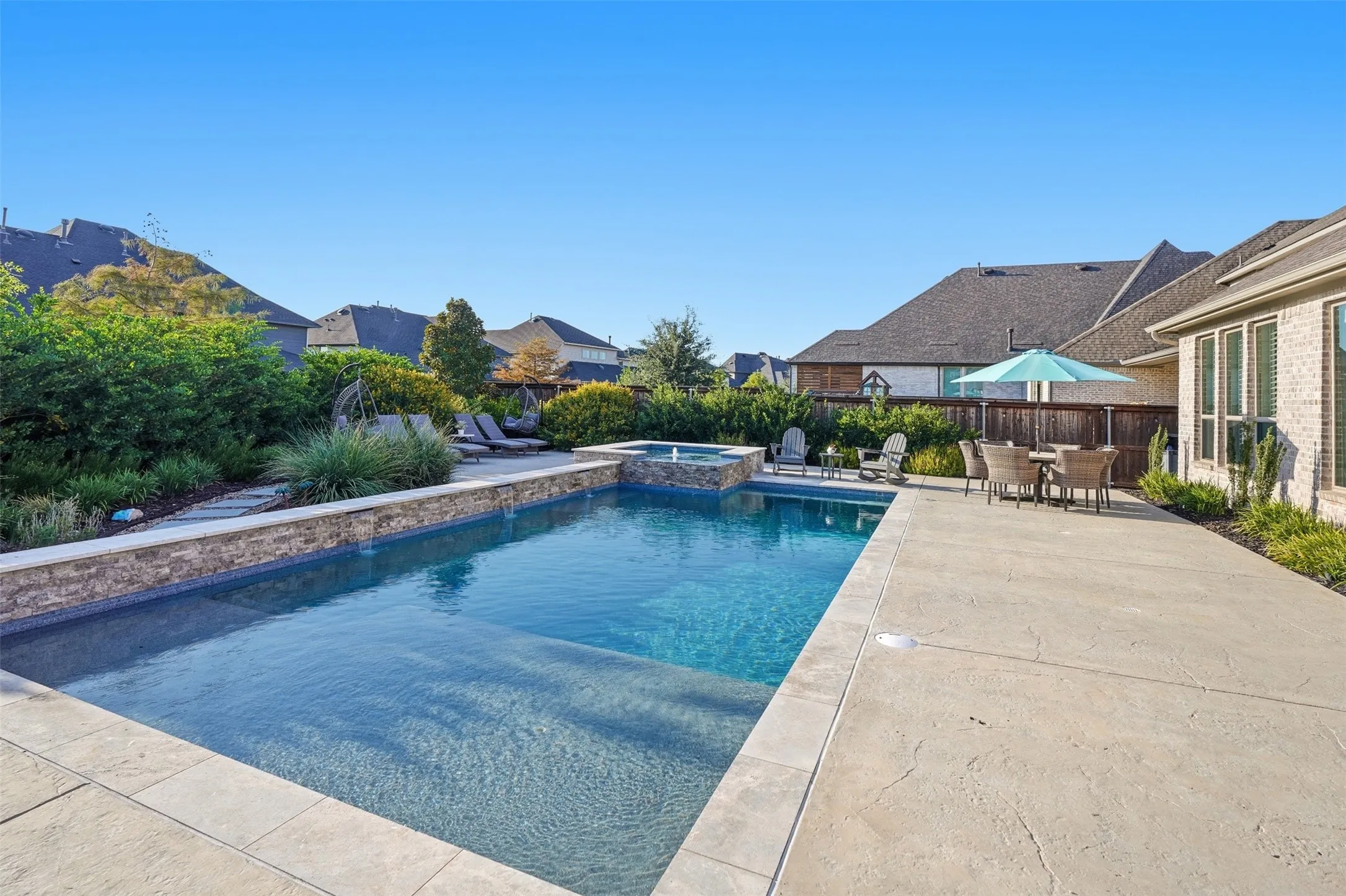 Expansive outdoor area featuring a swimming pool, integrated spa, and a stone-clad retaining wall