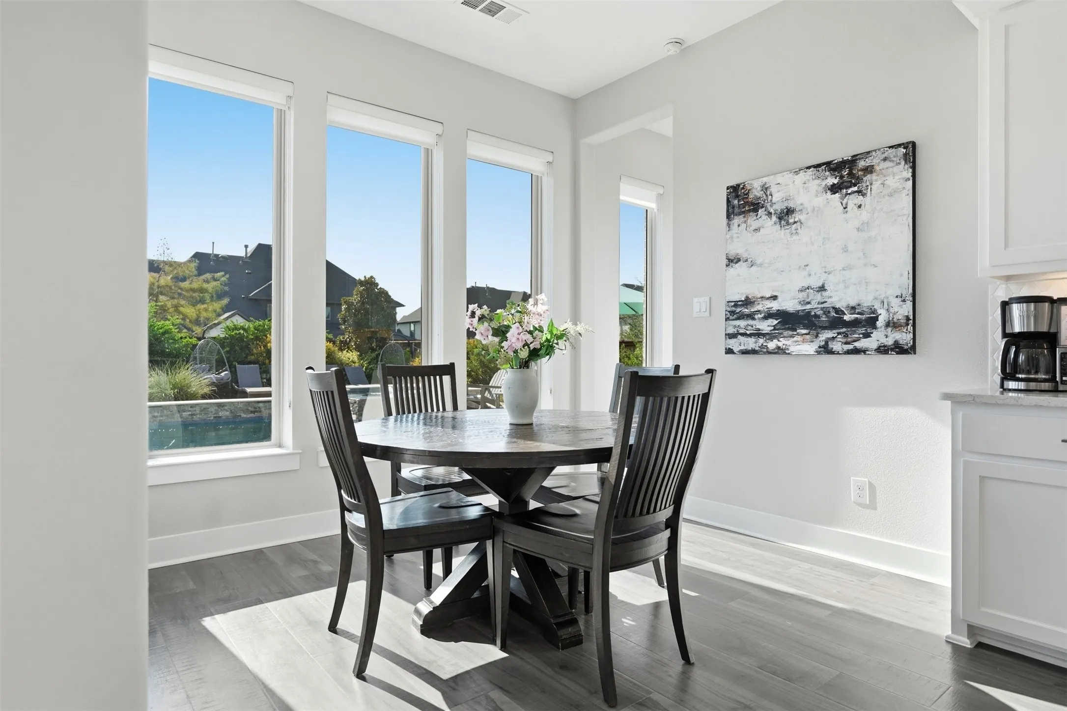 Expansive windows, wood-finish flooring, white cabinetry, and granite countertops