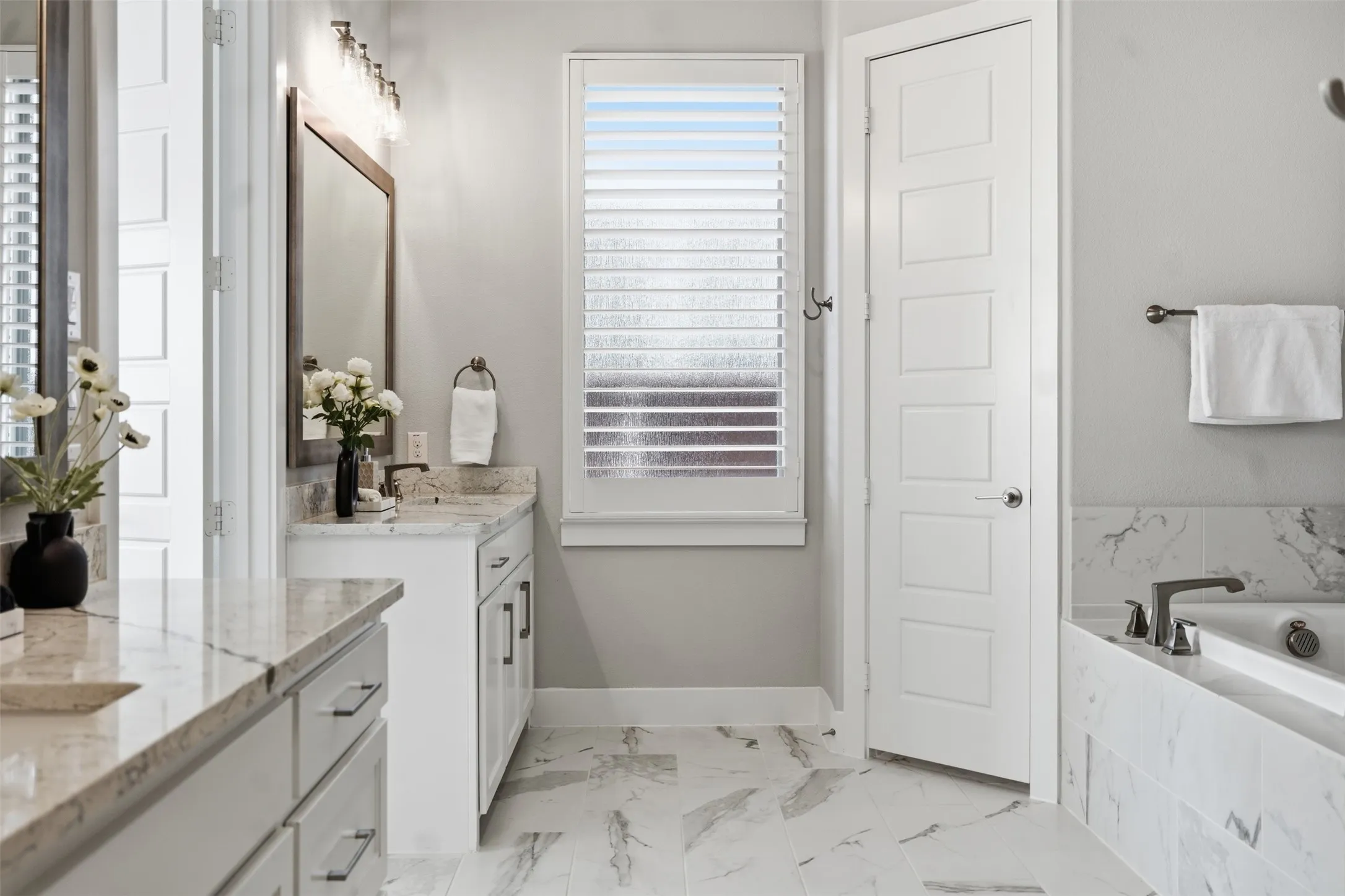 Dual vanity with light-toned countertops, white cabinetry with dark hardware, and undermount sinks