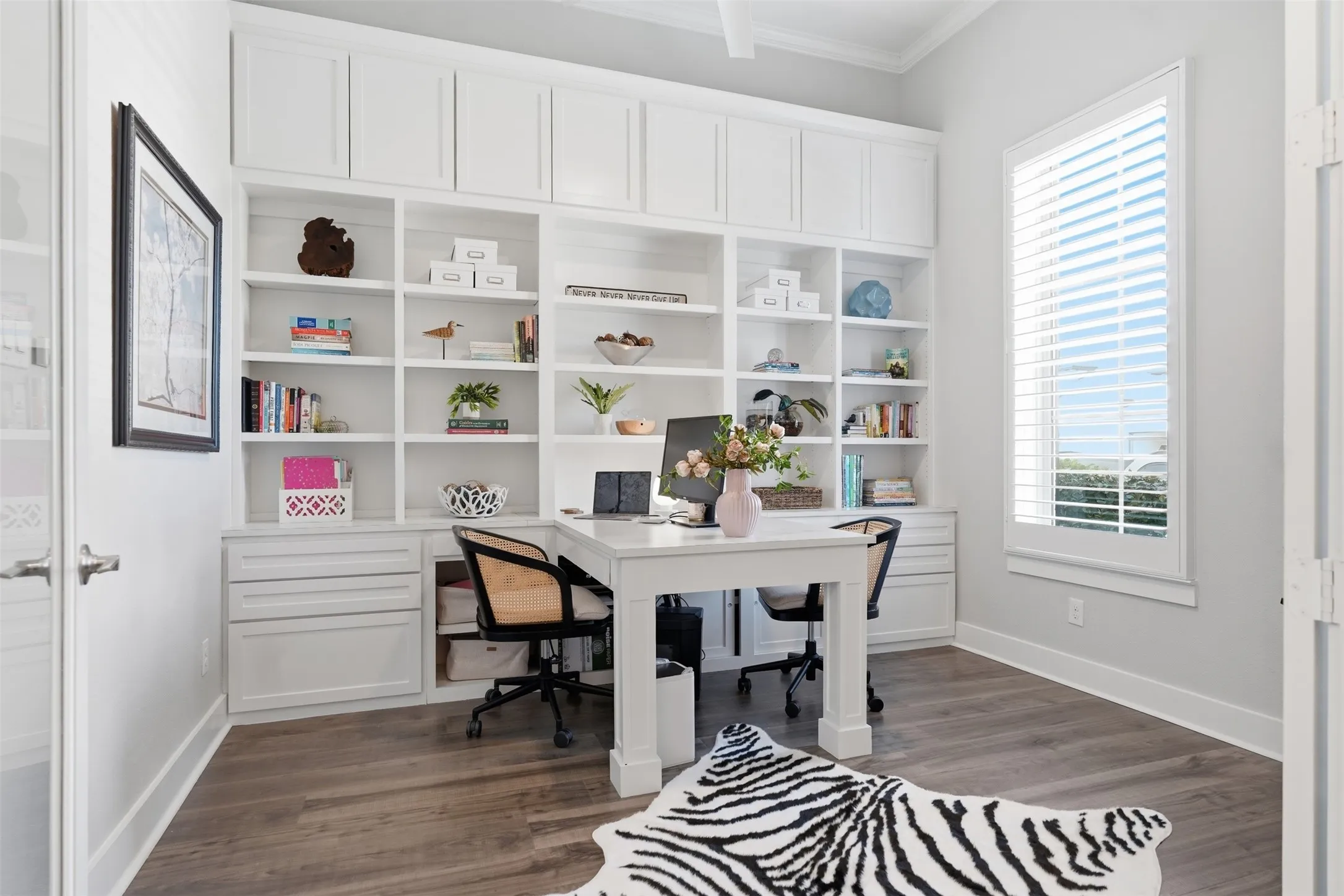 Built-in shelving with integrated cabinetry, wood-finish flooring, and a window with plantation shutters