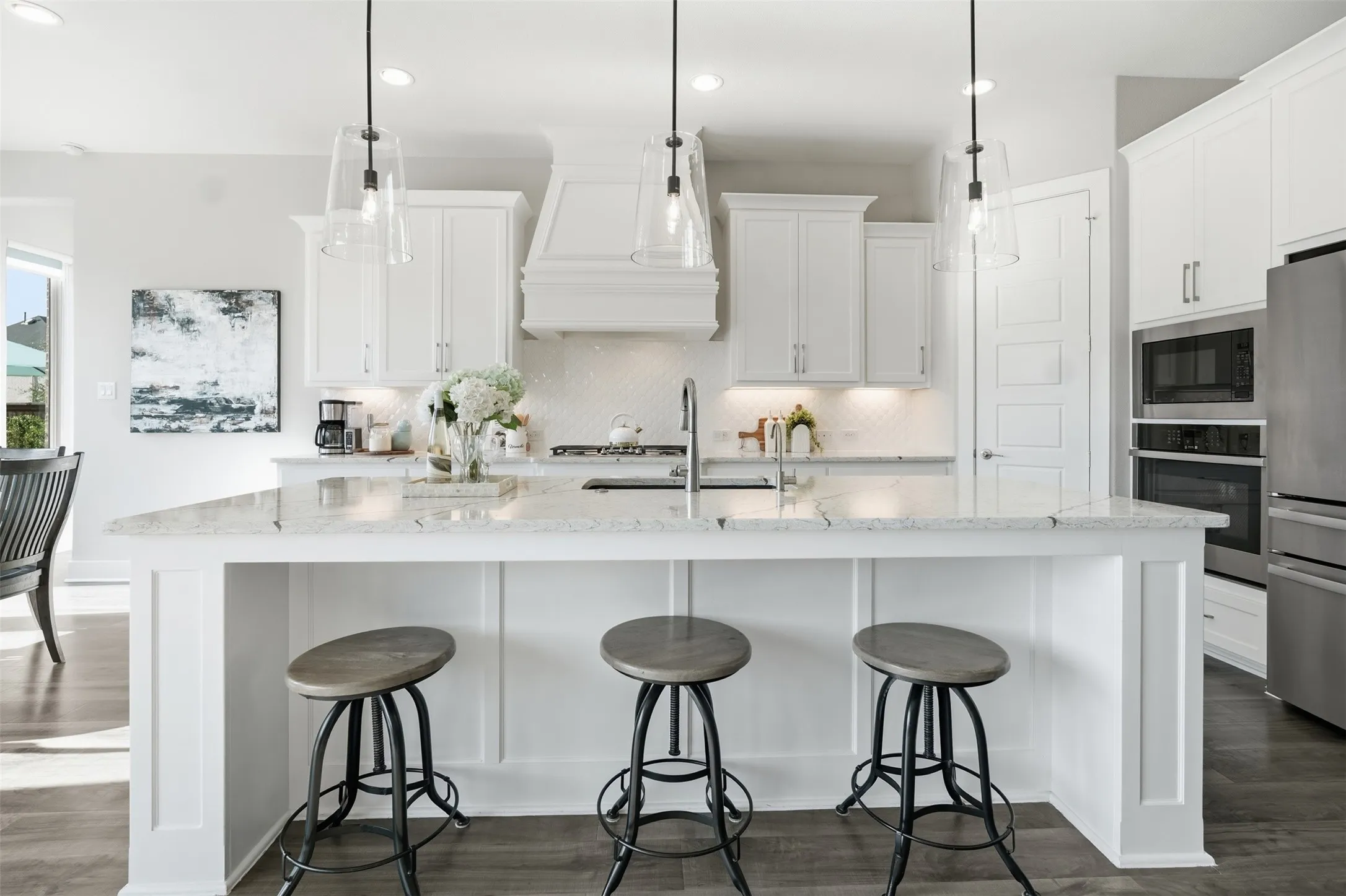 White cabinetry, stainless steel appliances, kitchen island, wood-finish flooring, and recessed lighting