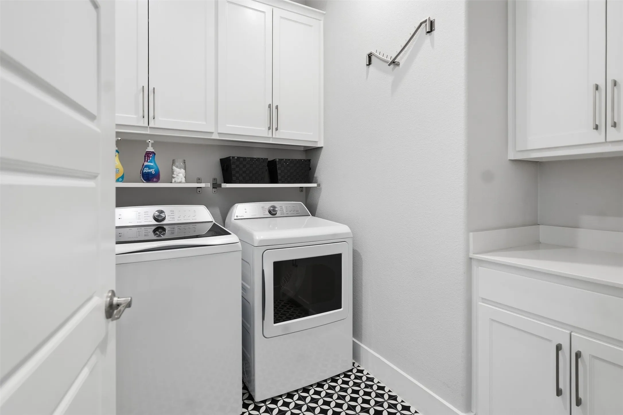 White shaker cabinetry, patterned floor tile, white shelving, and a white countertop