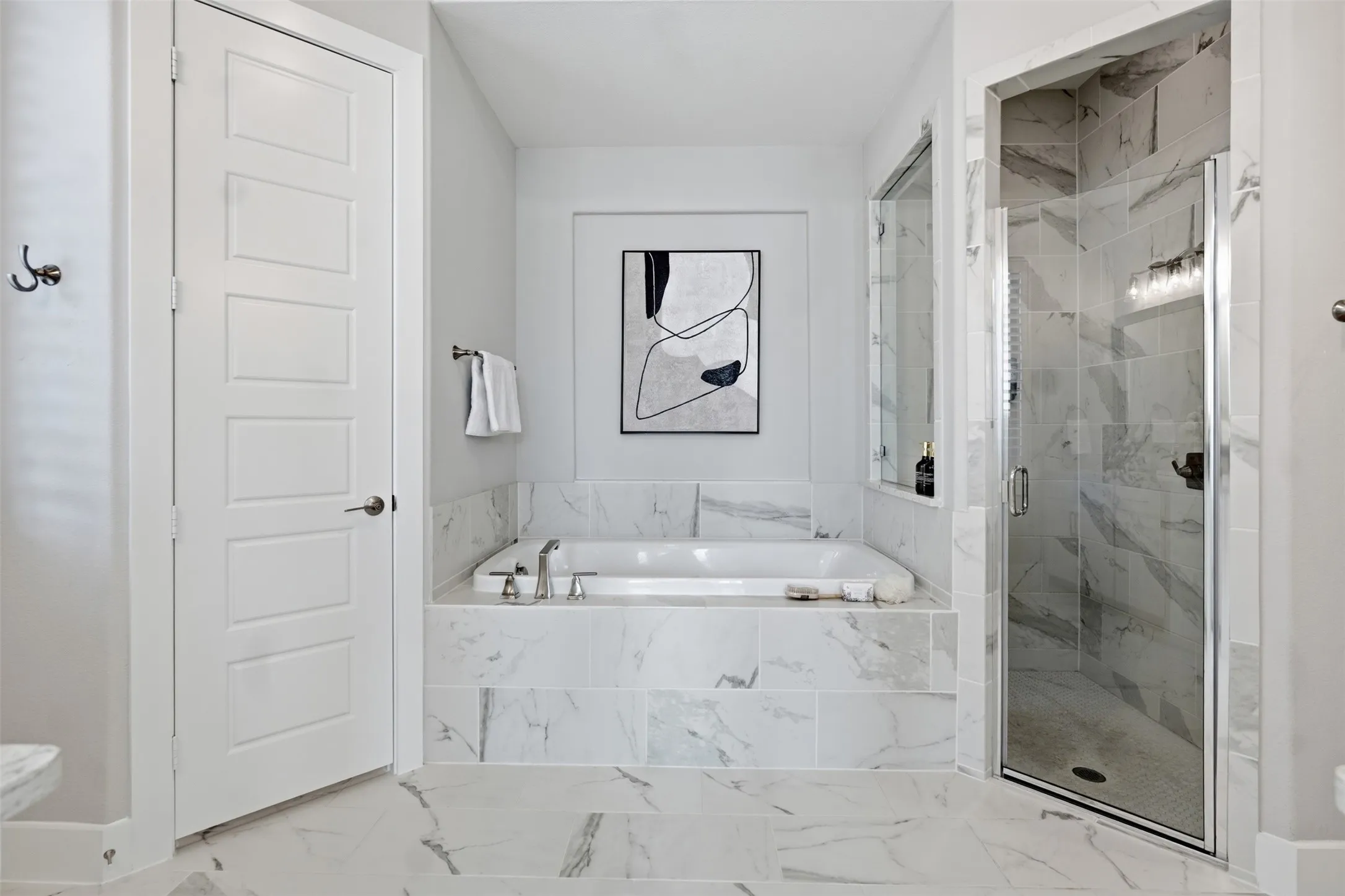 Soaking tub with deck-mounted fixtures, enclosed shower with glass door, and large format floor and wall tile