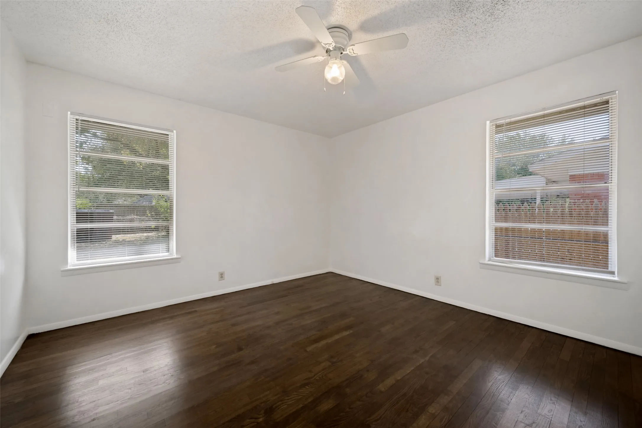 Wood-finish flooring, white walls, and a ceiling fan with integrated lighting