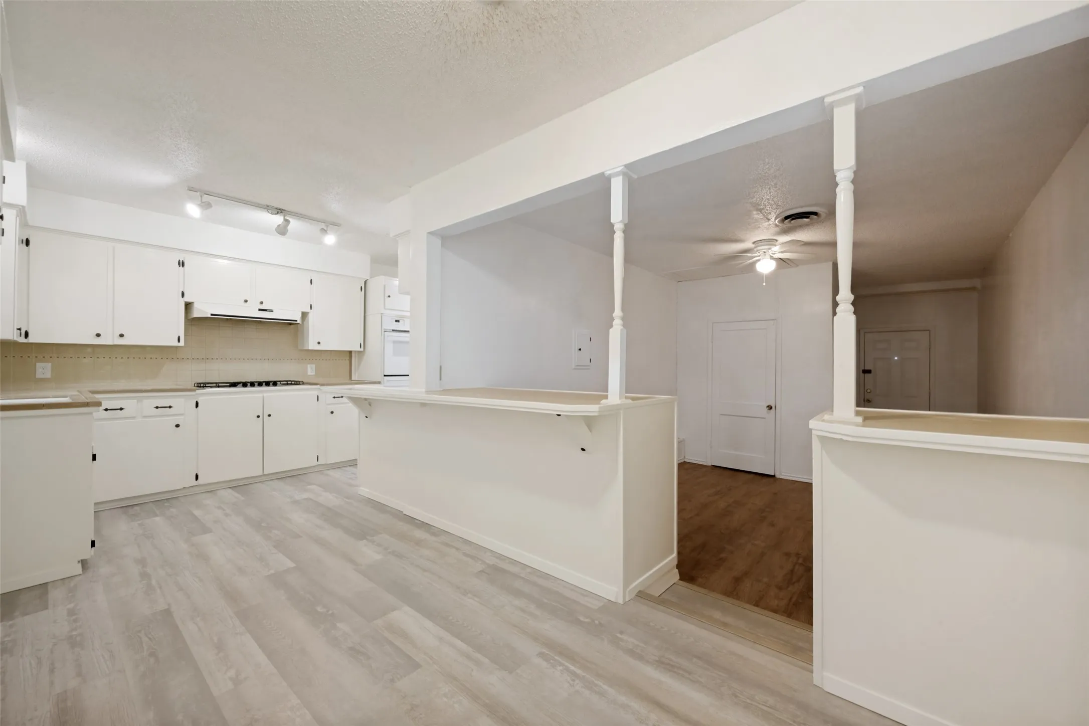 Kitchen featuring white cabinetry, light-toned countertops, and track lighting