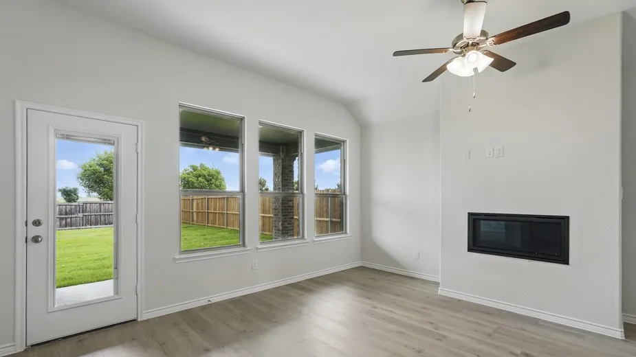 Recessed electric fireplace, ceiling fan with integrated lighting, wood-finish flooring, multiple windows, and a glass-paneled door