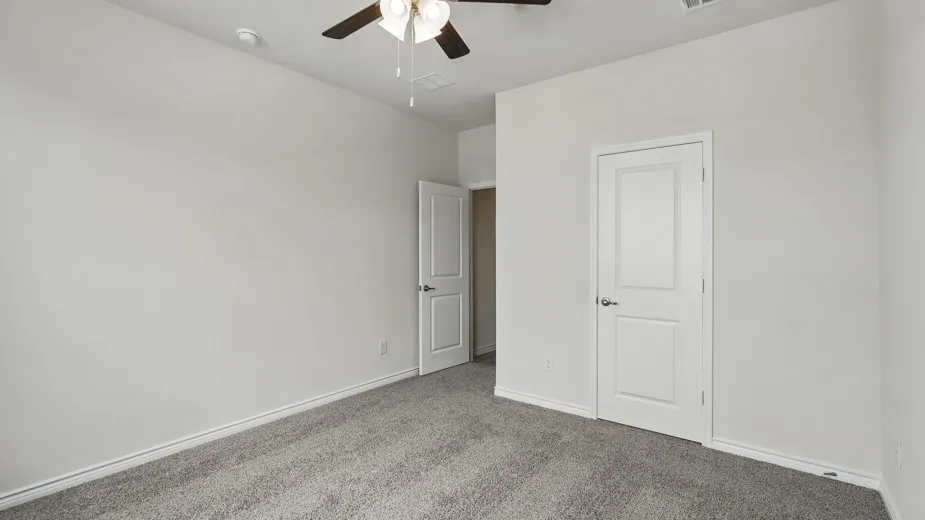 Plush gray carpeting, white trim, and a ceiling fan with light fixture