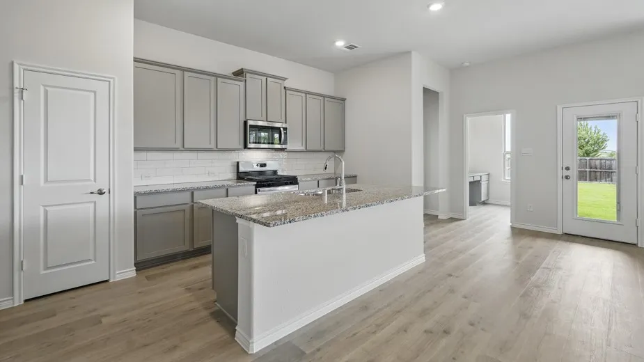 Kitchen featuring light wood-finish flooring, a kitchen island with stone countertops, gray cabinetry, and a white subway tile backsplash