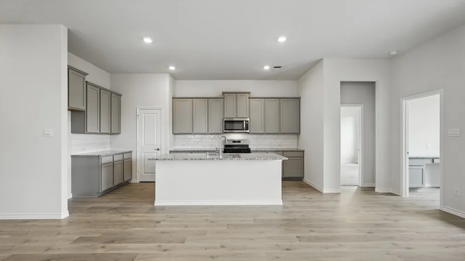 Open-concept kitchen with a central island, grey cabinetry, granite countertops, and subway tile backsplash