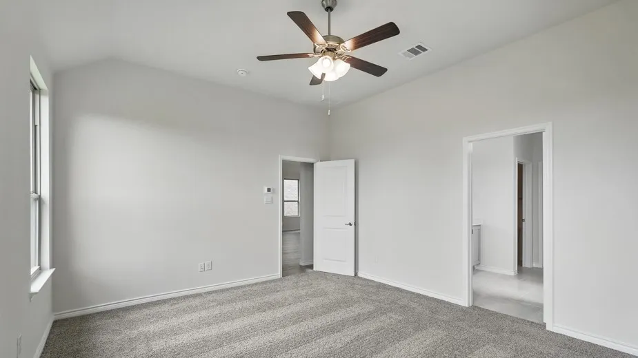 Vaulted ceiling, ceiling fan with integrated lighting, window with white trim, light grey carpeting, and white interior doors