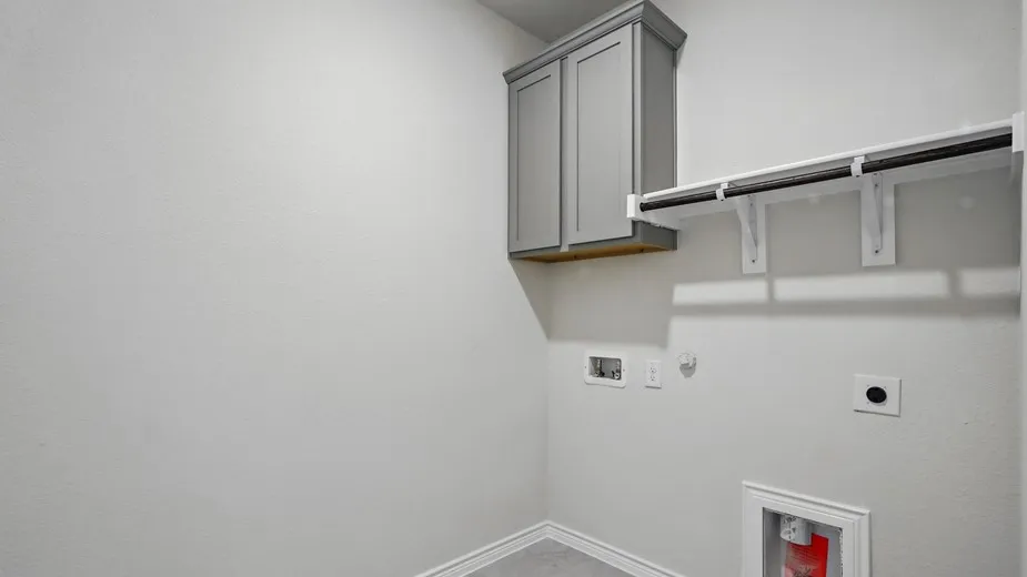 Dedicated utility space featuring overhead cabinetry, an integrated hanging rod, and textured walls