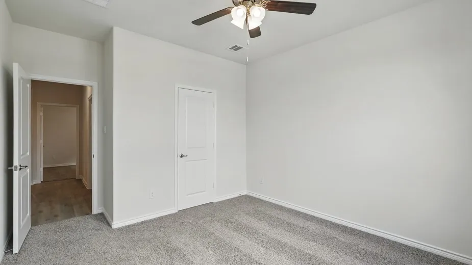 Carpeted flooring, white walls, white trim, white interior doors, and ceiling fan with lighting