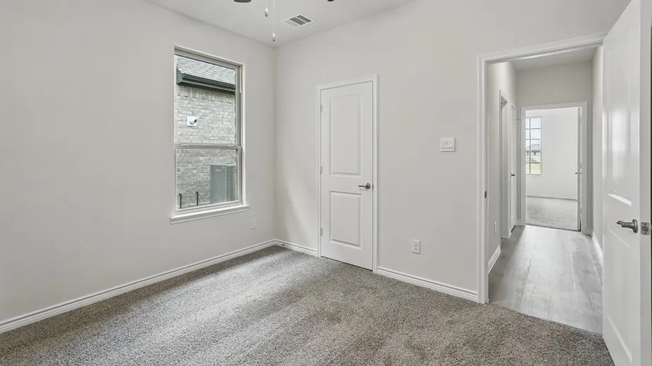 Light gray carpeting, white painted walls, and a ceiling fan with light fixture