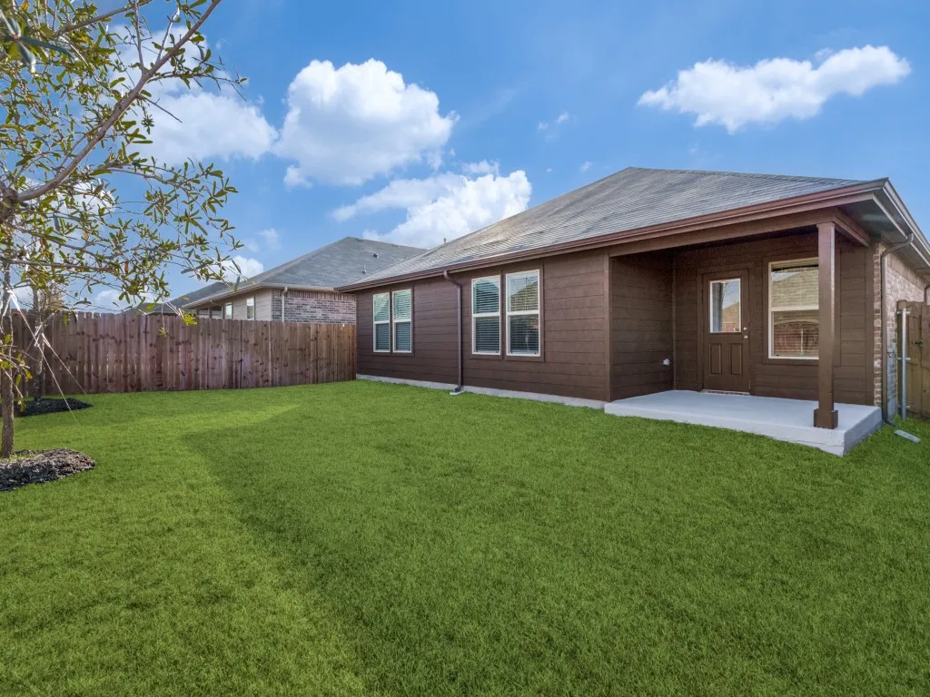 Expansive grassy yard with wood fencing, a concrete patio, and a covered porch